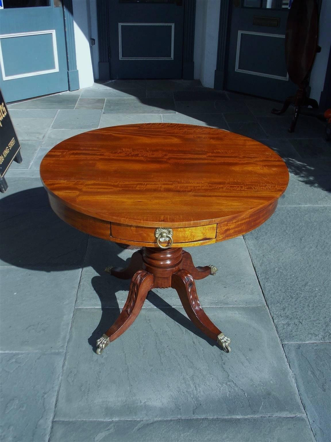 American Federal mahogany two-drawer drum table with the original brass pulls, turned bulbous pedestal and terminating on acanthus carved saber legs with the original lions paw brass casters, Boston, Early 19th Century.