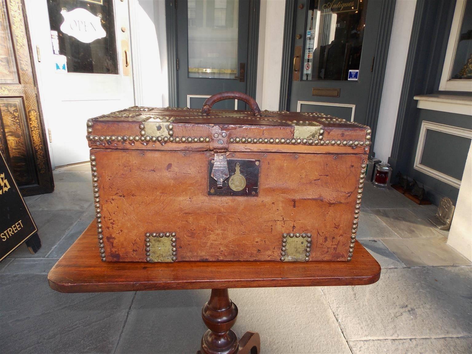 American leather wharf chest with exterior brass mounts, brass studs, carrying handle, stamped locking mechanism and the original paper lined interior. Engraved on lid Boston Wharf Company, Mid-19th Century.
