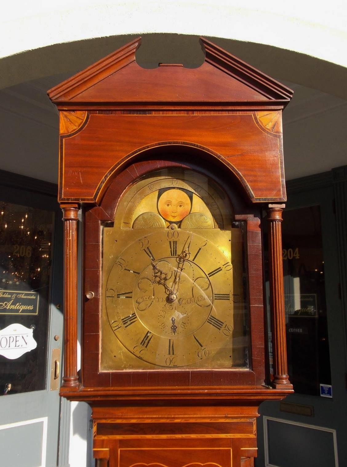 English mahogany and satinwood inlaid 30 hour tall case clock with Palladian cornice, fanned satinwood inlaid corners, fluted columns, engraved brass face with Roman numerals and clock maker, flanking quarter columns, crotch mahogany trunk with