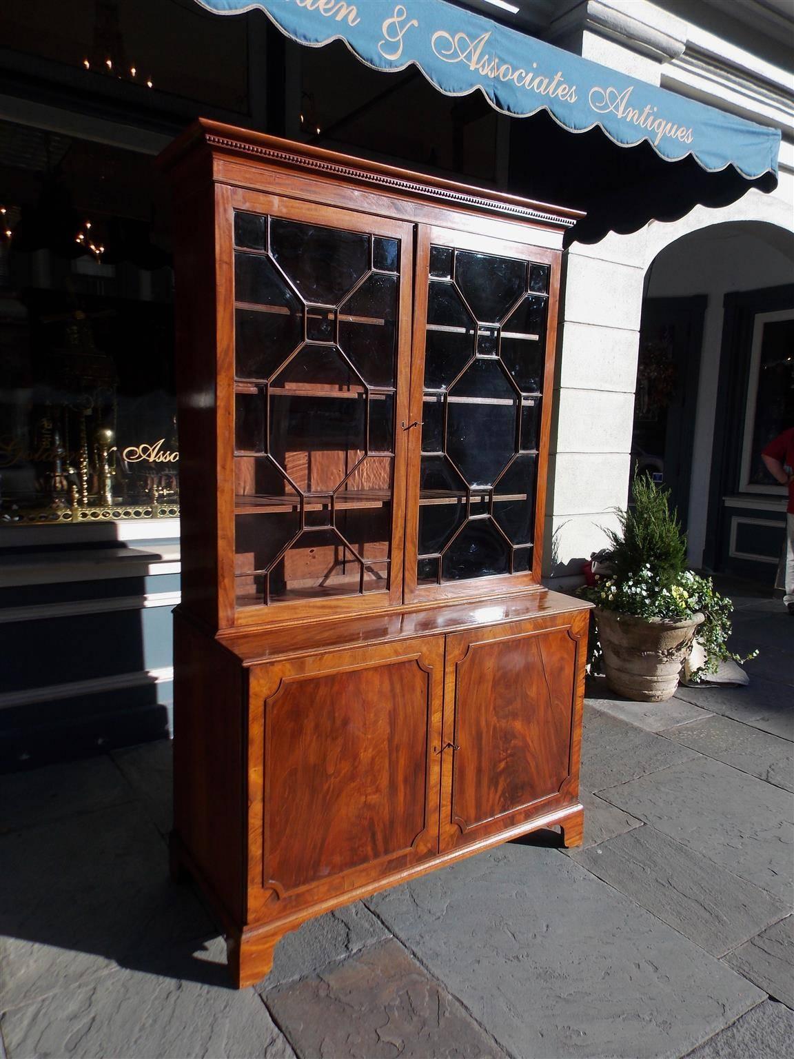 American Charleston Chippendale mahogany china press with a upper case carved molded edge cornice, dental molding, original hinged glass doors with mullions, adjustable interior shelving, lower case flanking book matched doors revealing interior