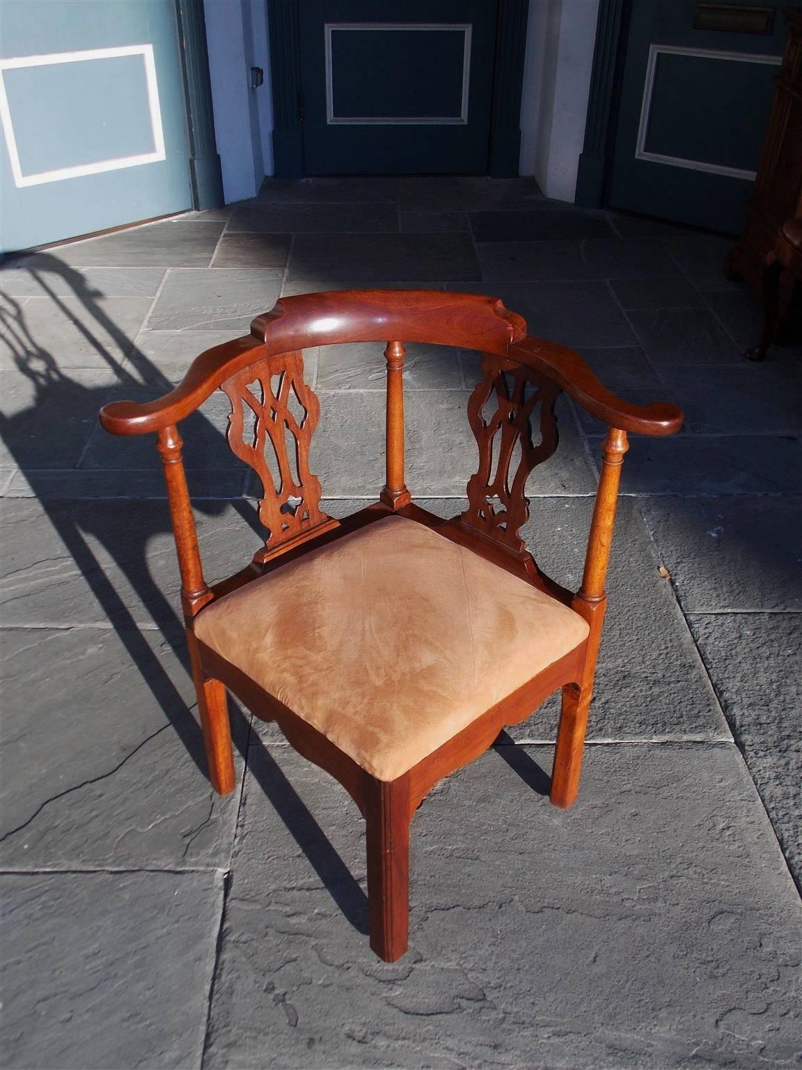 English Chippendale mahogany corner chair with a carved centered back, scrolled outset arms, flanking carved splat backs, a scalloped carved skirt and terminating on molded reeded legs. Retains the original removable seat frame under the upholstery,