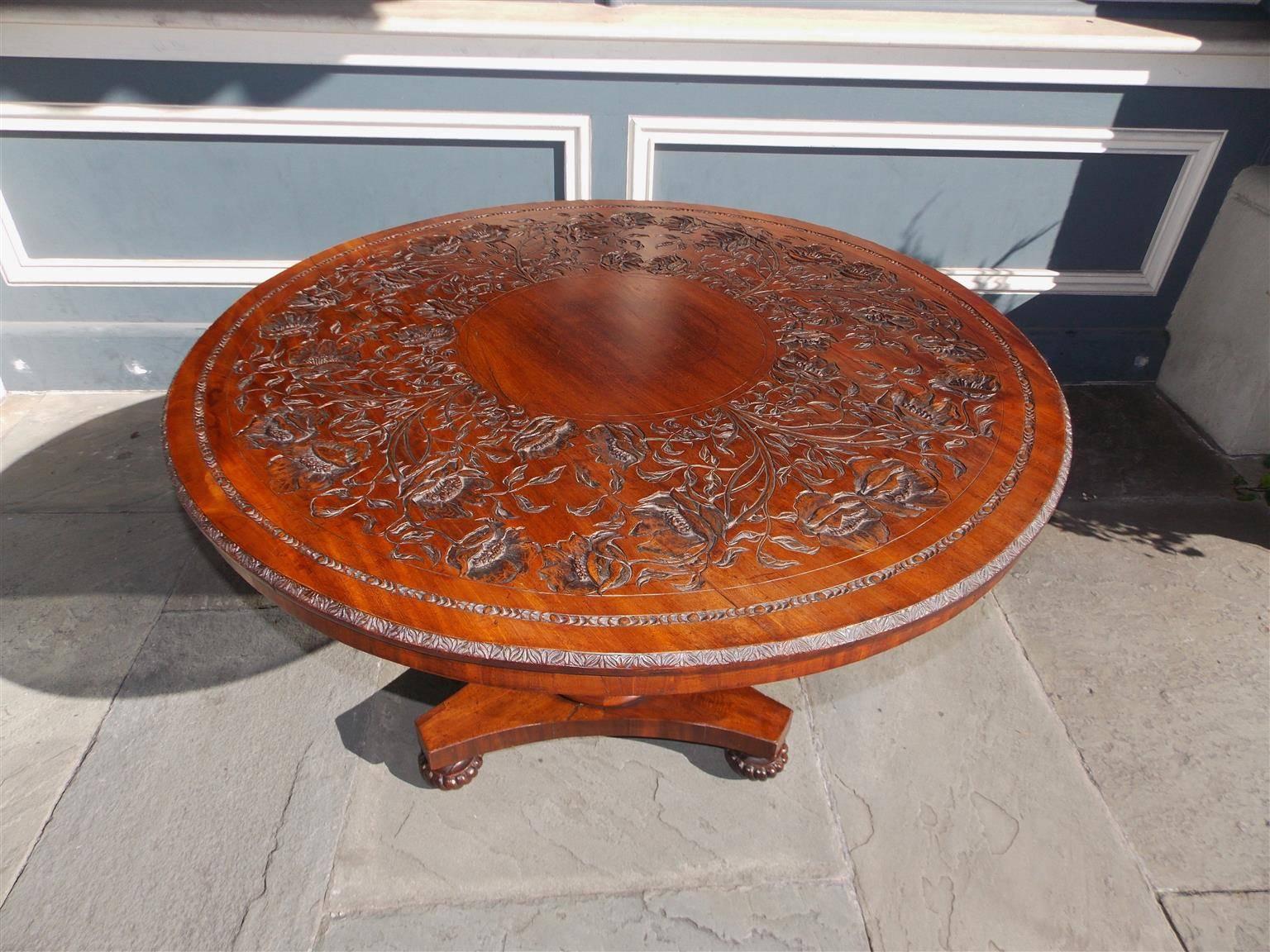 English mahogany center table with a decorative carved hibiscus floral top, spiral bulbous filigree carved pedestal and terminating on a tripod base with the original melon feet, Early 19th Century.