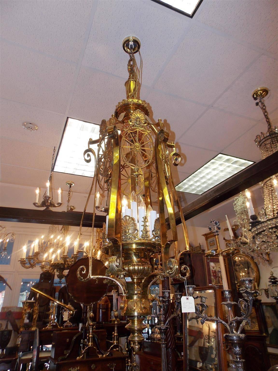 American monumental brass twenty one light hanging lantern with a urn finial top, flanking sea shell oval medallions, scrolled exterior acanthus supports, interior shell and foliage motif, and terminating on a graduated finial with a pine cone