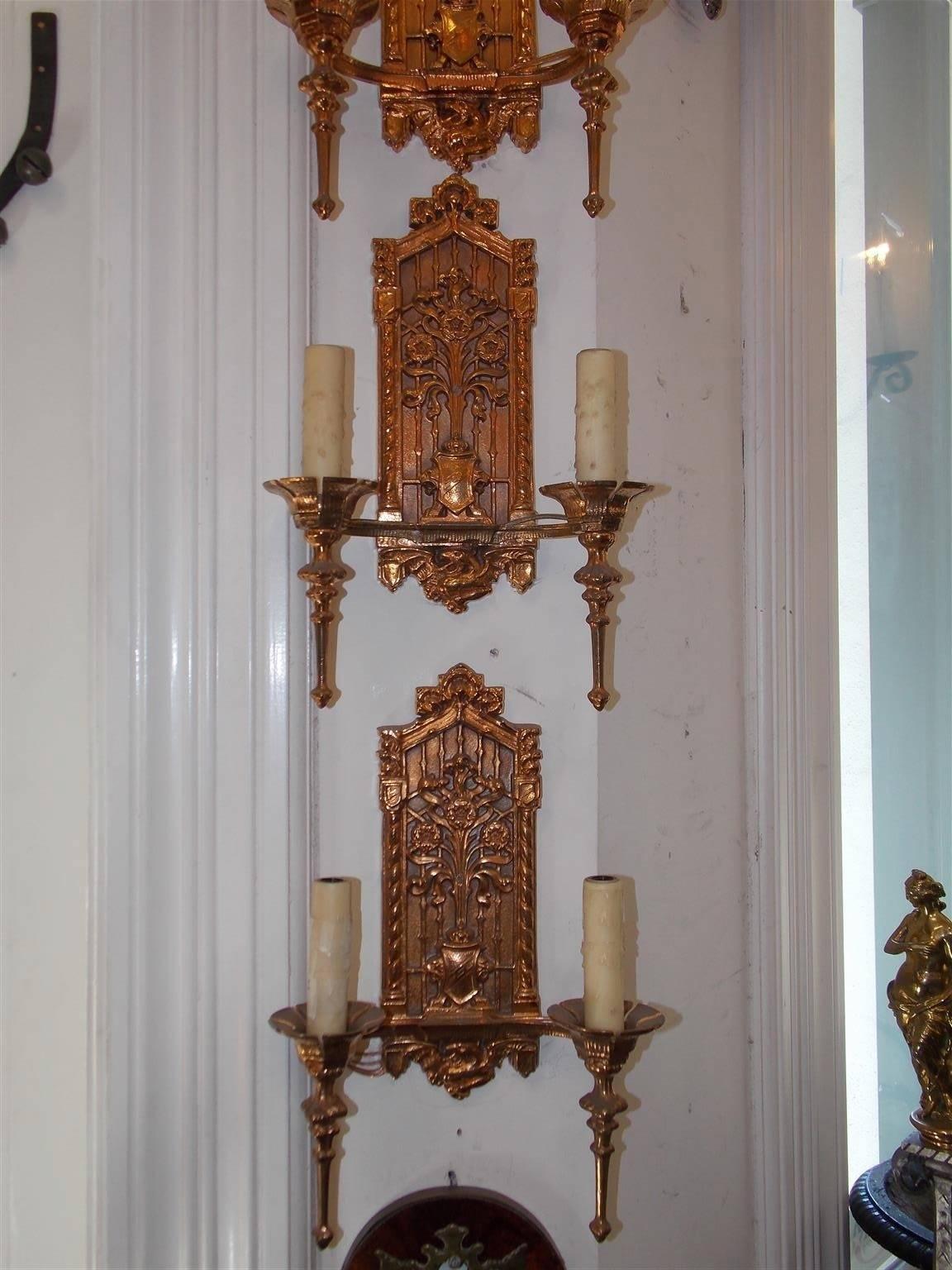 Set of six English two-arm bronze sconces with foliage paladin cornices , centered floral coat of arms, fluted bobeches with tampered spheres, and terminating with a lower centered decorative winged gargoyle, Early to Mid-19th century. Sconces were