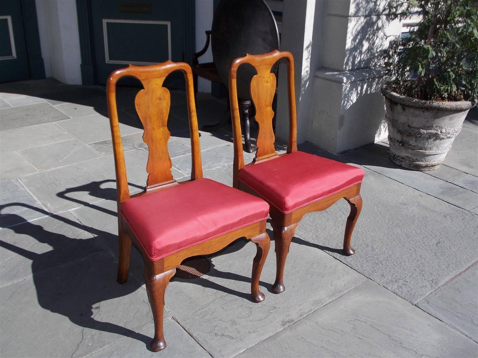Pair of American Queen Anne side chairs with carved flanking cresting rails, centered vase splat back, upholstered seats, serpentine carved skirt , and terminating on cabriole legs with pad feet, Pennsylvania, Early 19th Century.