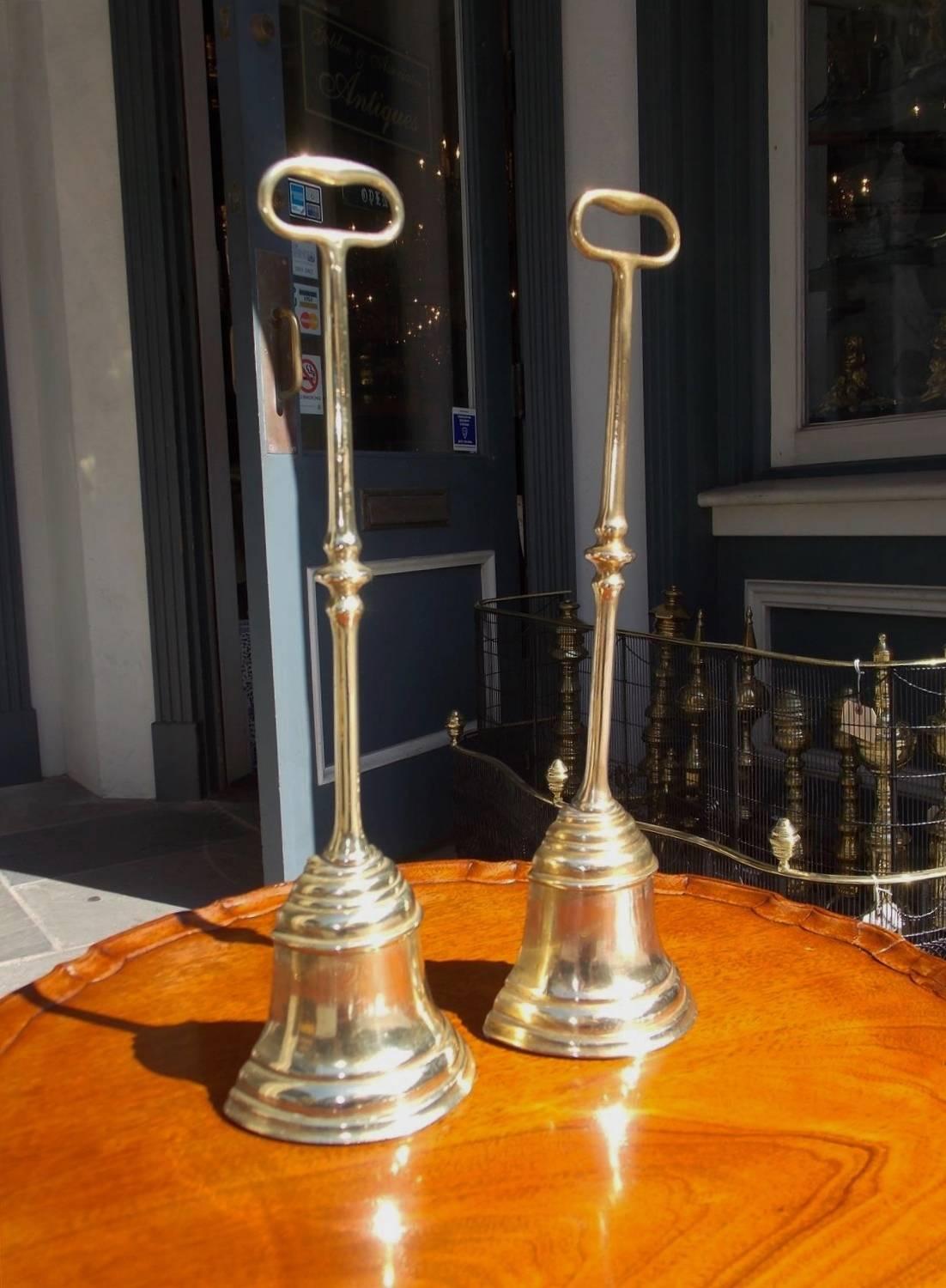 Pair of English federal brass bell shaped doorstops with matching carrying handles, bulbous columns and lead inserts. All original, Late 18th century.