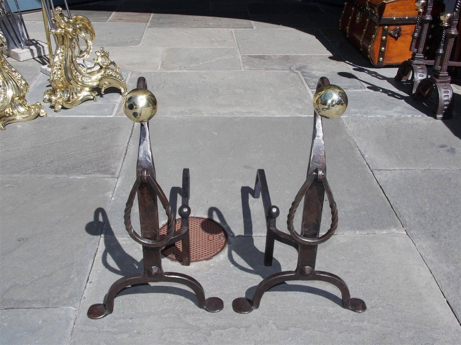 American wrought iron and brass ball top goose neck andirons with decorative spiral rings, tapered plinths, matching log stops and terminating on stylized penny feet, Early 19th Century.