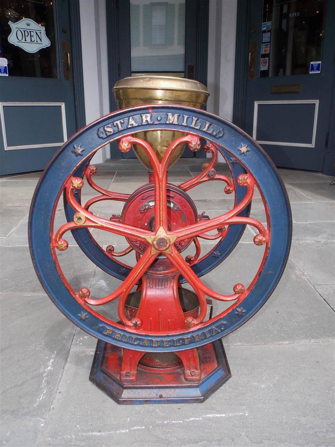 American cast iron coffee grinder with the original blue and red paint. Grinder has the original brass hopper, wood handle, and catch pail as well. Model # 10, Star Mill, Philadelphia, Late 19th Century.