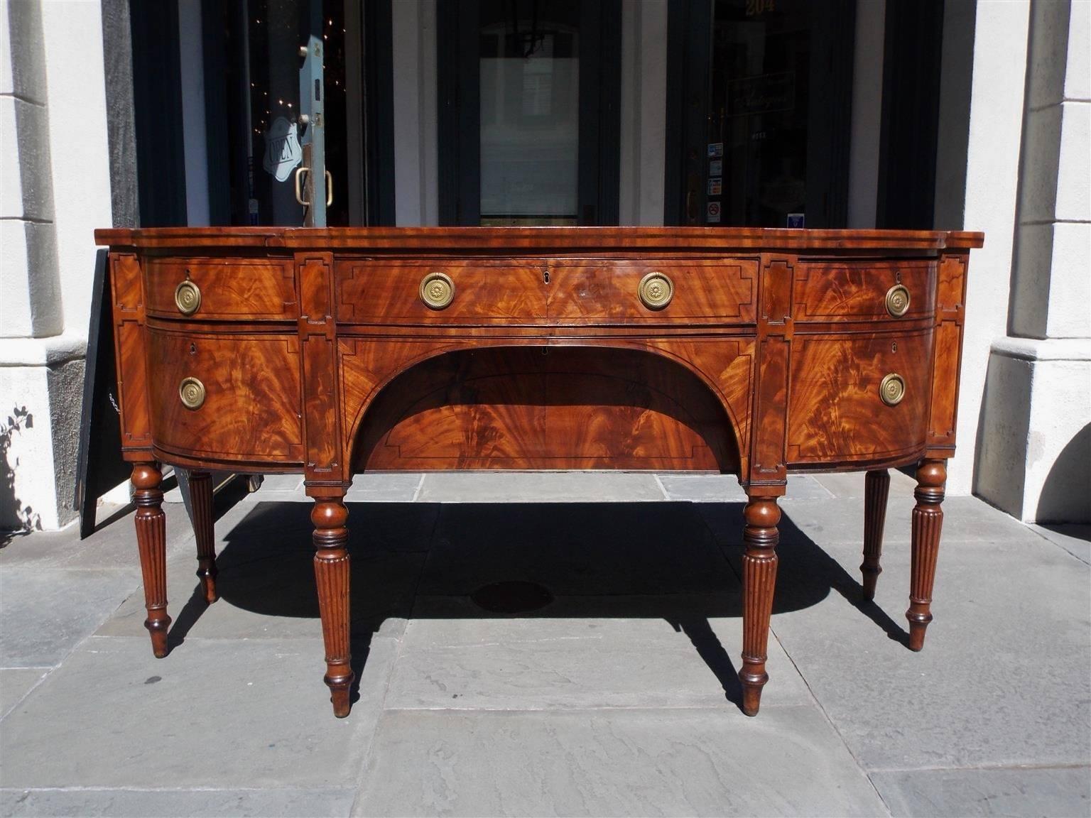 English Regency mahogany bow front sideboard with a upper case centered long drawer, flanked by a cutlery drawer and bottle box drawer, lower case arched centered silver drawer, flanked by a hinged side cupboard door, ebony string inlay drawer