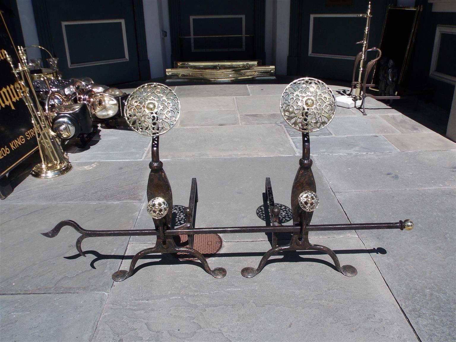 Coppia di androni inglesi in ottone e ghisa con doppio medaglione decorativo floreale, zoccoli modanati, ganci per spiedo con attizzatoio, fermi a sfera coordinati e terminanti su gambe a voluta con piedini, metà del XIX secolo. L'attizzatoio a