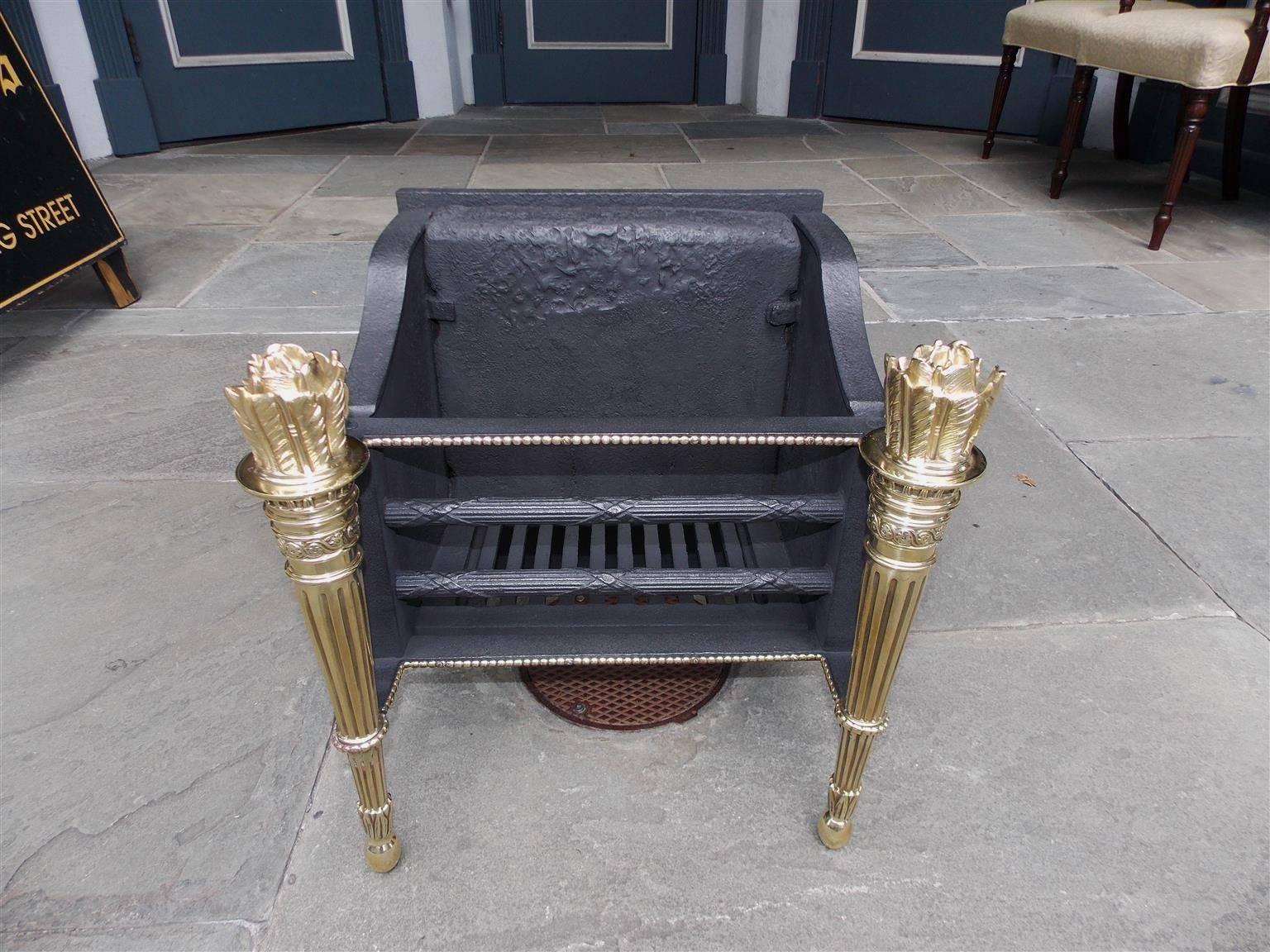 French cast iron and brass coal grate with flanking flame fluted torchieres, elegant double brass row of beading, decorative cross hatching horizontal bars, and fitted with the original interior heat reflector, Early 19th century.