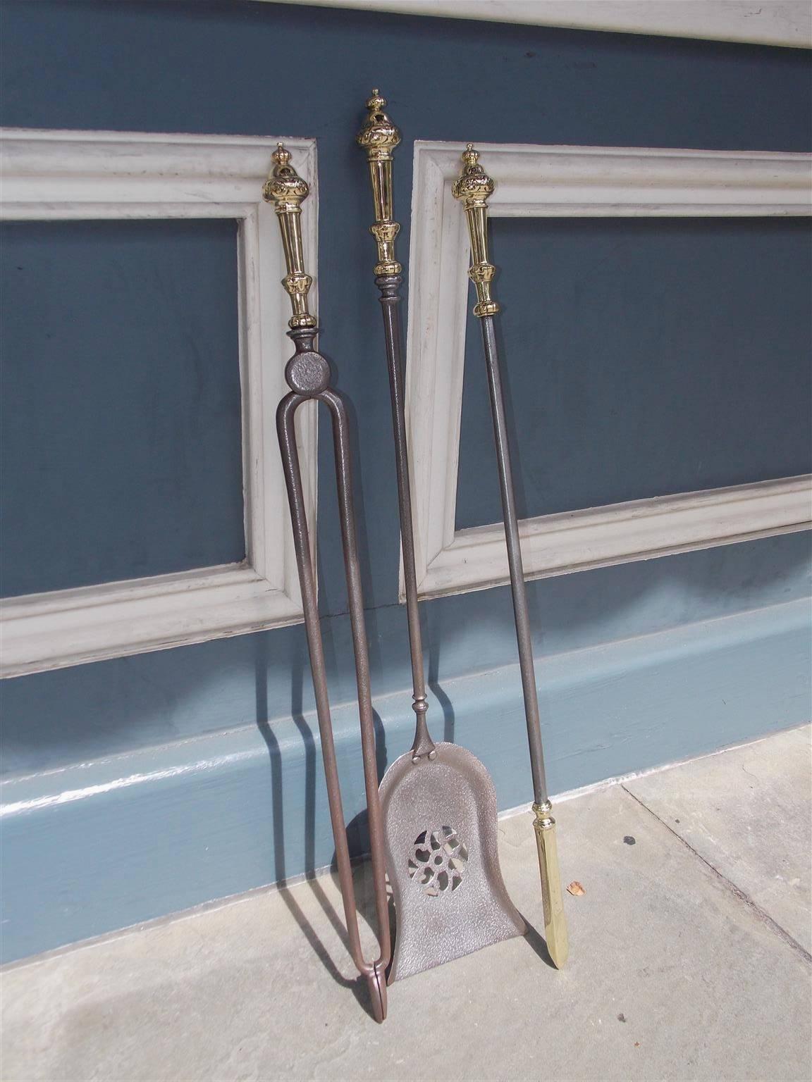 Set of three English polished steel and brass fire place tools with decorative urn finials and foliage handles. Set consist of pierced floral shovel, tong, and brass tipped poker for stoking the fire place, Early 19th century.