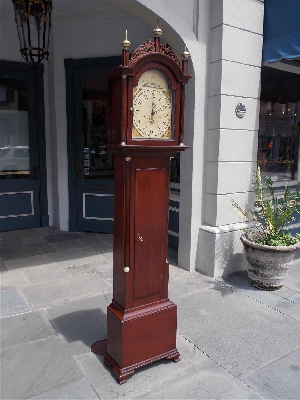 American Federal mahogany one day tall case clock with the original brass ball finials resting on three carved upper capitals, decorative intertwined fret work, arched hood with brass mounted mahogany side columns, hinged glass door revealing a hand