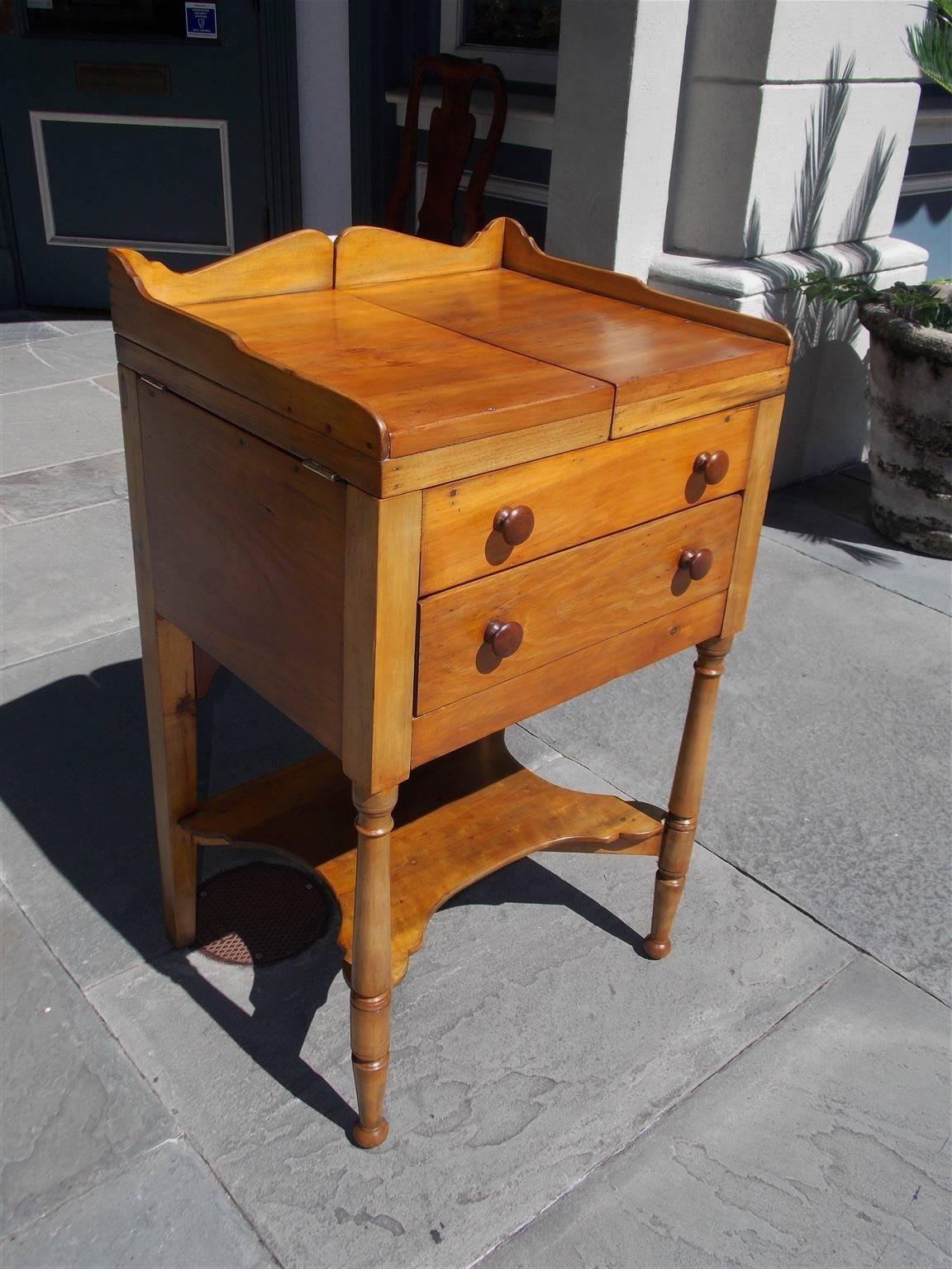 American Sheraton maple and cherry one drawer wash stand with scalloped gallery, hinged top revealing a circular fitted interior for basin, sliding rear adjustable mirror, original cherry wood knobs, lower supported shelf, and terminating on the