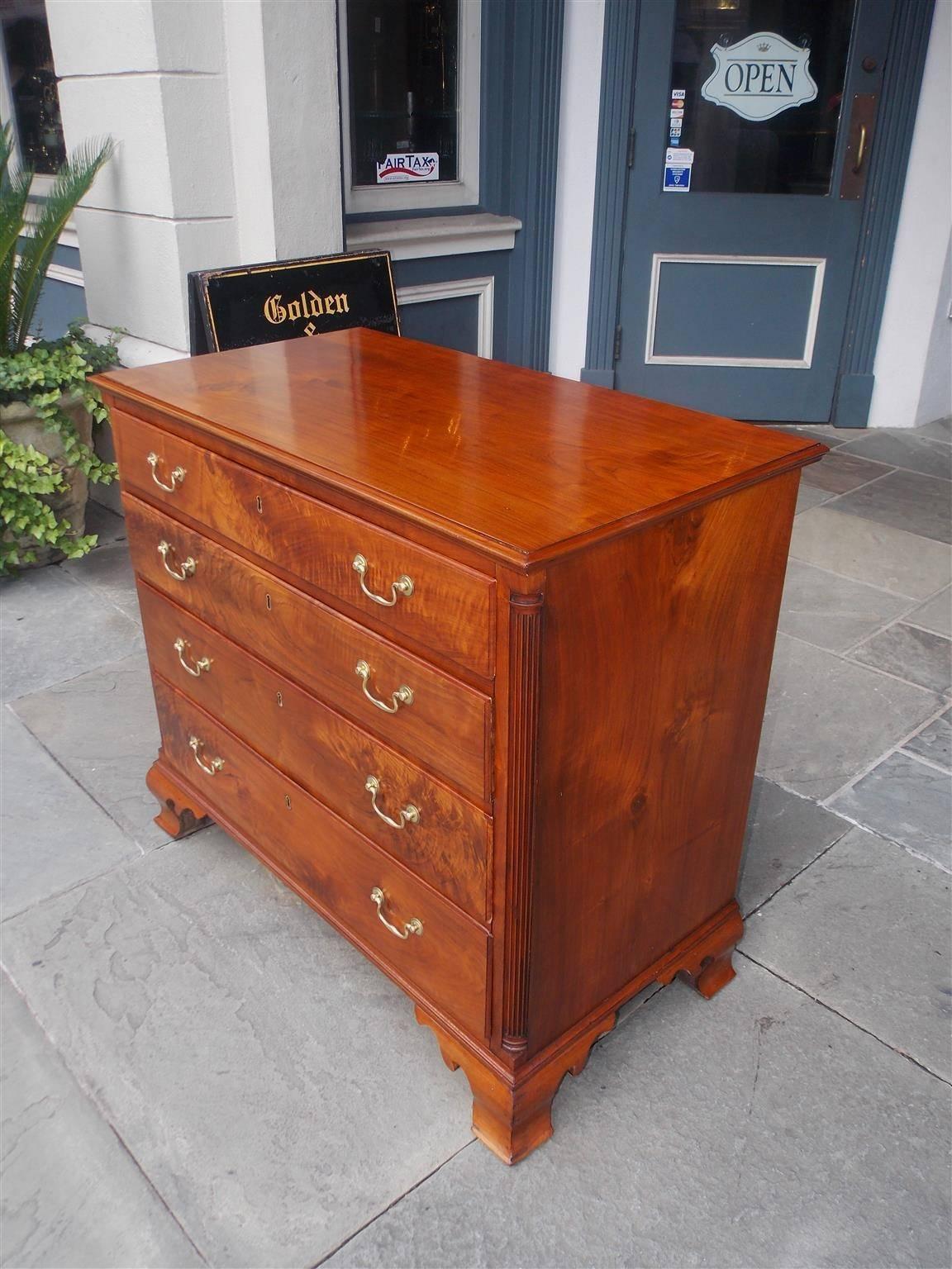 American Chippendale figured walnut chest of drawers with a carved molded edge top, flanking fluted carved quarter columns, four graduated dove tailed drawers with the original brasses, and terminating on the original molded edge ogee bracket feet.