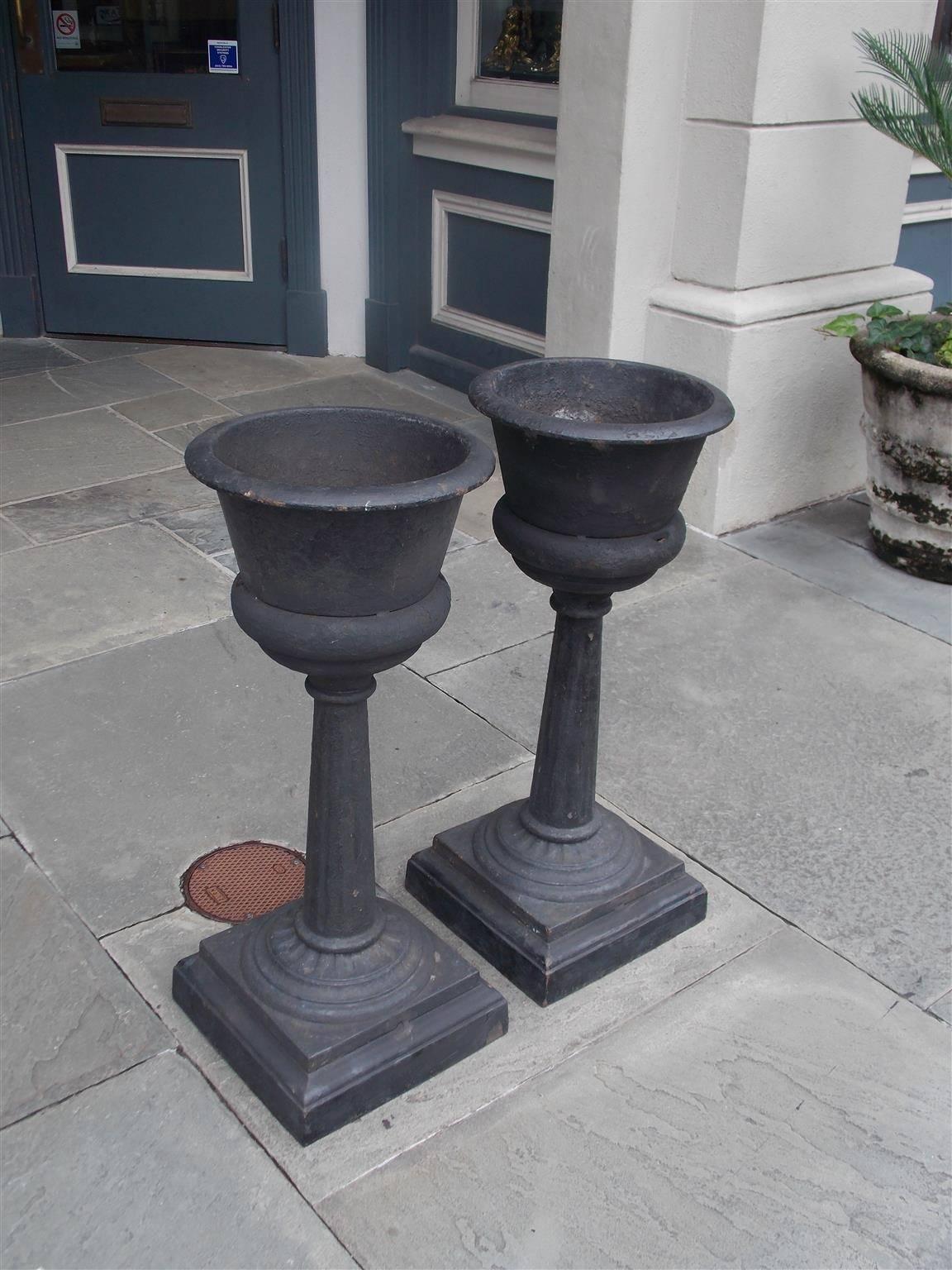 Pair of French cast iron and painted urn garden planters with tapered fluted ringed columns supported by circular squared step back plinths, Mid-19th century. Pair retain the original cast iron inserts for water drainage. 