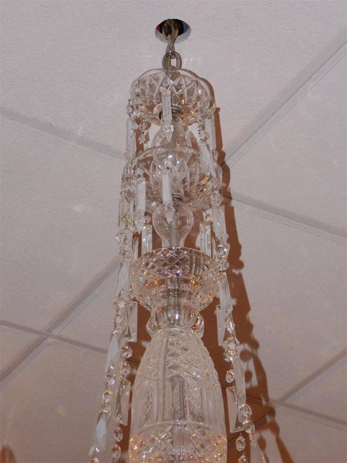 Lustre en cristal taillé anglais avec une colonne centrale en cristal bulbeux, quatre bras en spirale à volutes, des prismes de connexion en cascade, et se terminant par une grande coupe en cristal taillé et une boule à facettes. Fin du 19e siècle.