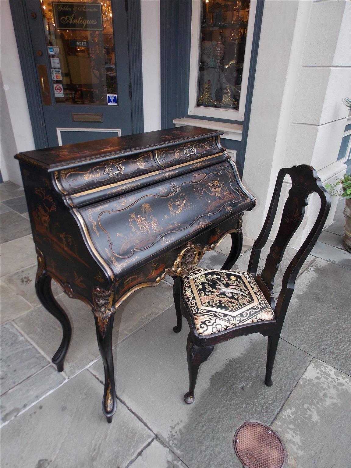 English Chinoiserie black lacquered and gilt fall front writing desk with figural landscape scenes, two upper case drawers, fitted interior, leather writing surface, centered gilt carved floral cartouche, and is terminating on the original