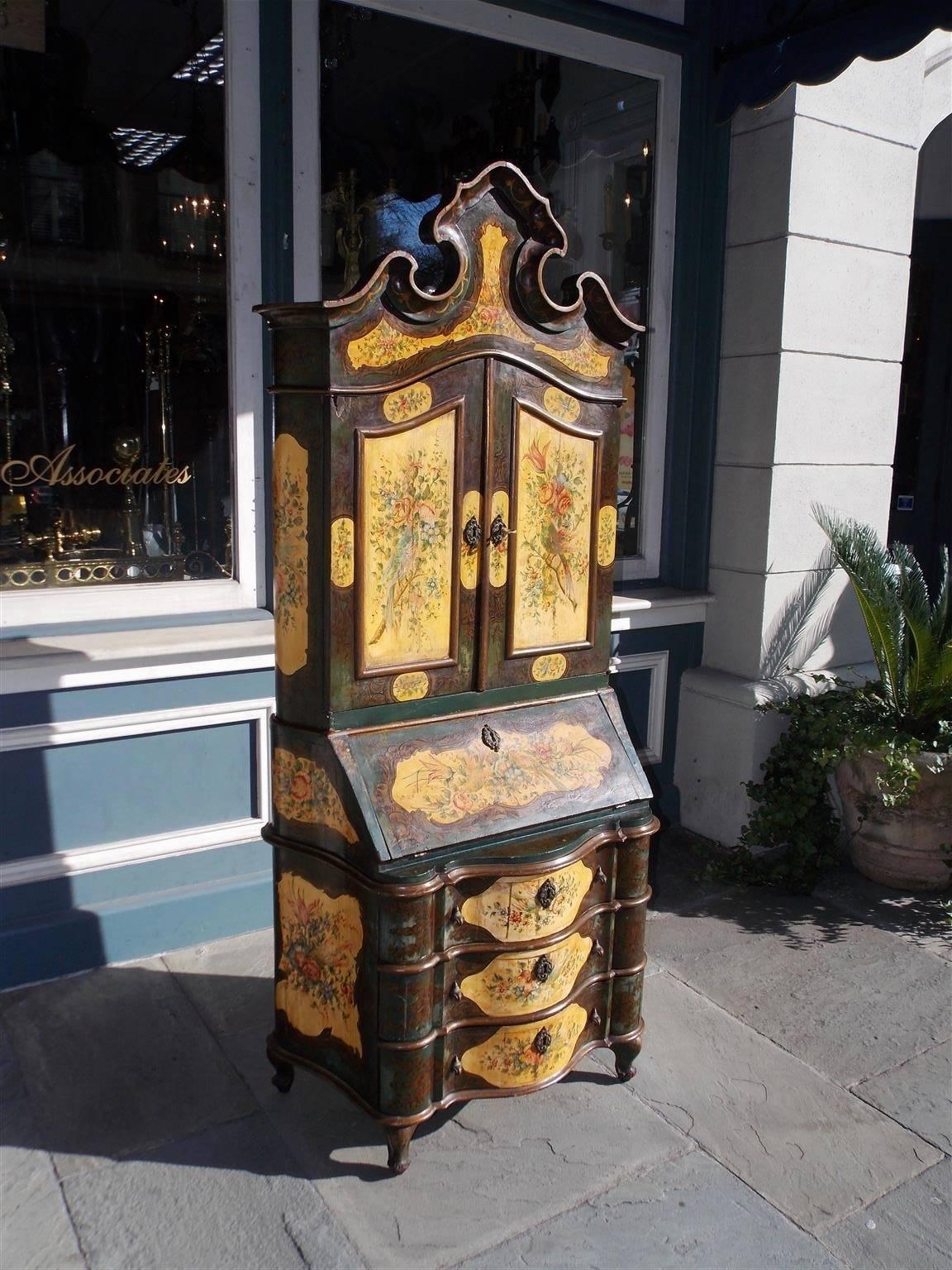 Venetian blind door secretary with a carved scrolled decorative cornice, upper case bookcase with hand-painted parrots and foliage, slant top reveling a fitted interior desk, three lower case drawers with rounded corners, original brasses, and