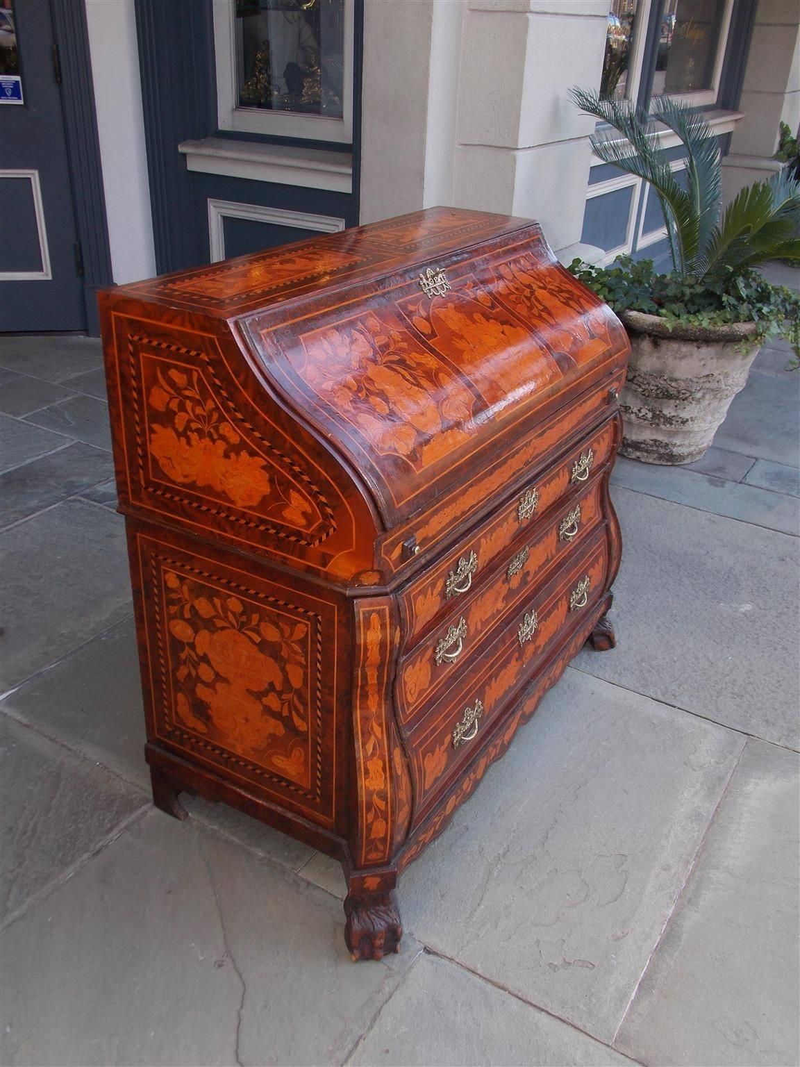 Dutch Marquetry burl walnut Bombay figural and foliage desk with exotic exterior inlays, fitted interior, three lower case drawers, original urn brasses, carved scalloped skirt, and terminating on the original lions paw feet, Mid-19th century.