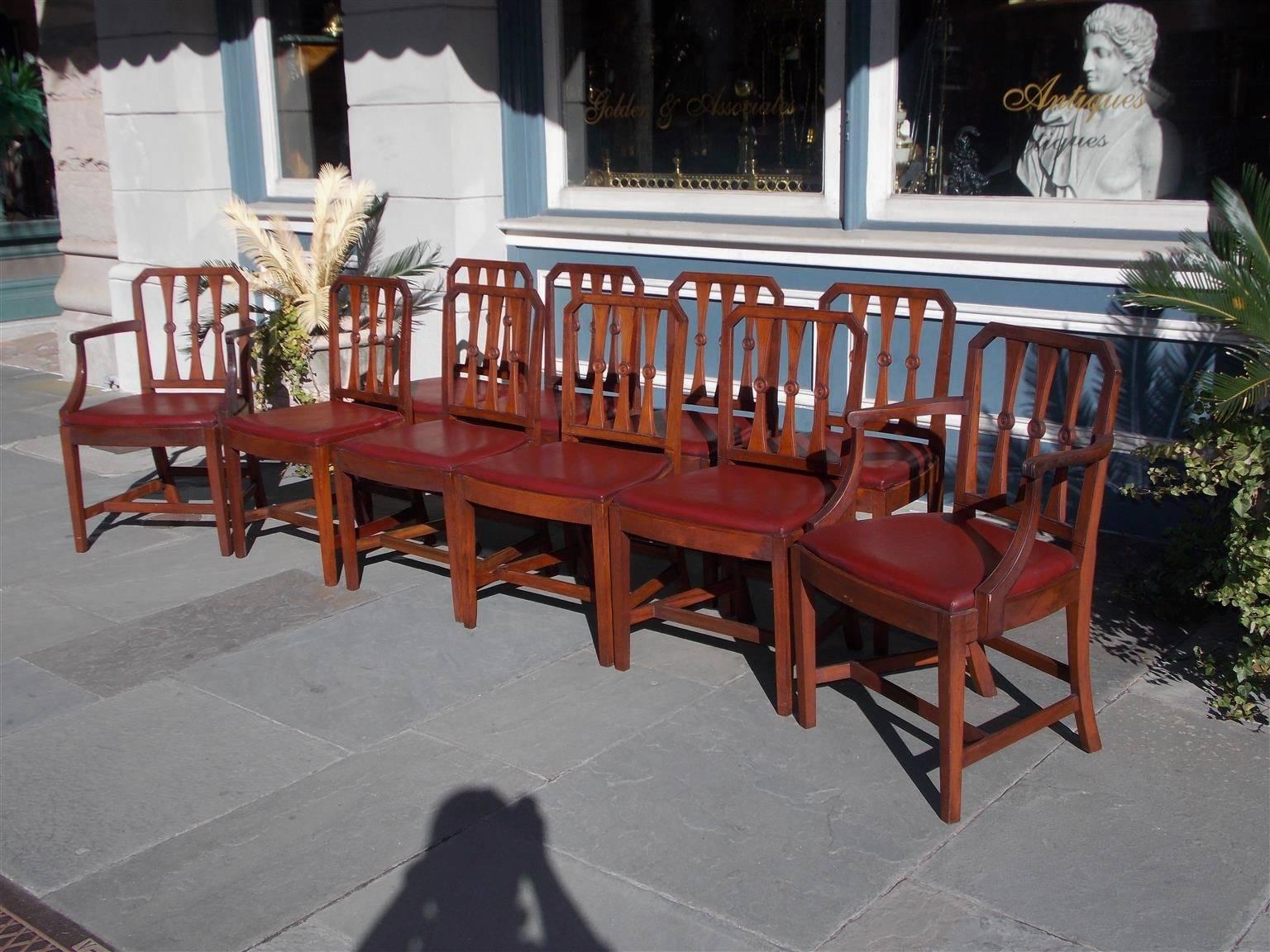 Set of Ten English Regency mahogany dining room chairs with carved molded edge rails, tapered circular splat backs, removable leather seats, and terminating on squared legs with connecting stretchers.  Early 19th Century.  Set consist of two arms