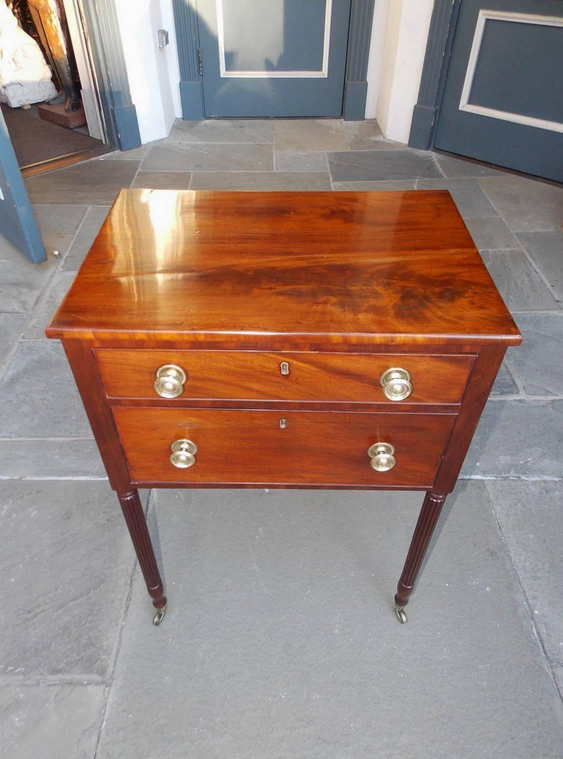 American Sheraton mahogany two-drawer side table with a carved molded edge top, the original brasses, and terminating on reeded ringed legs with the original brass casters. Table is finished on all sides and secondary wood consists of poplar