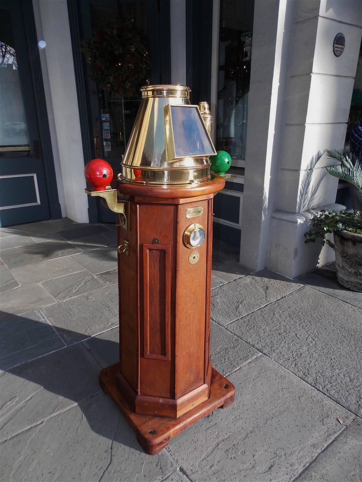 This highly desirable and fine nautical instrument is made of carved mahogany with a brass and glass hood covering a gimbaled compass and flindler's tube with cap. The eight sided binnacle was deck mounted and has painted cast iron port and