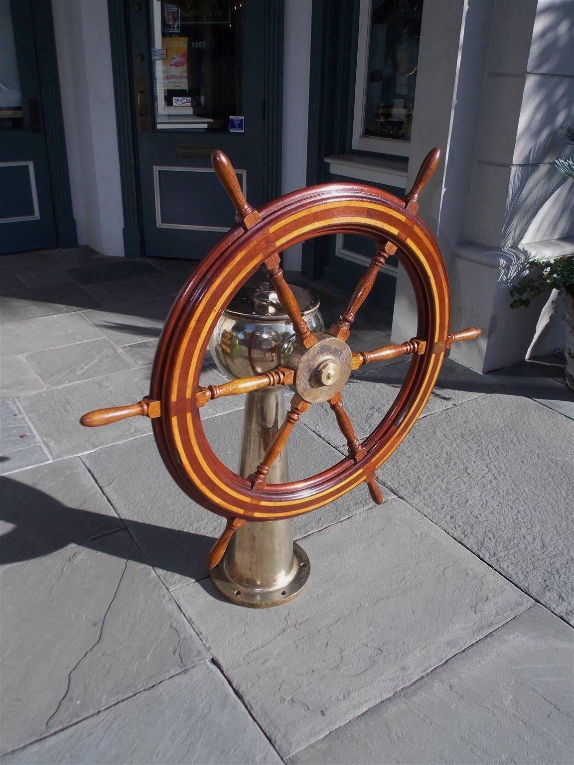 American mahogany nautical ship wheel with a centered brass hub, six turned oak spindles, outer ring on wheel inlaid with holly, and mounted to a solid brass geared pedestal, Late 19th Century. Stamped by maker : American Engineering Company,