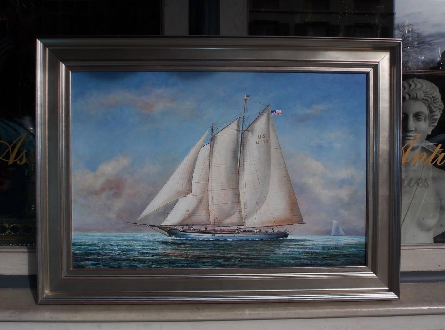 American Nautical oil on canvas of two masted schooner yacht under full sail with American flag, crew on deck, second vessel in distance, and mounted in a silver gilt frame, Early 20th century. Signed D. Thyler.