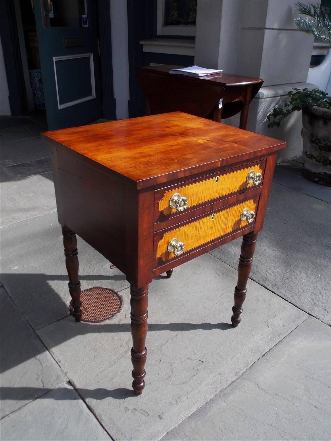 American Sheraton cherry, mahogany, and tiger maple two-drawer stand with a carved molded one board top, the original floral brasses, and terminating on turned ringed bulbous legs. Table is finished on all sides and secondary wood consists of poplar
