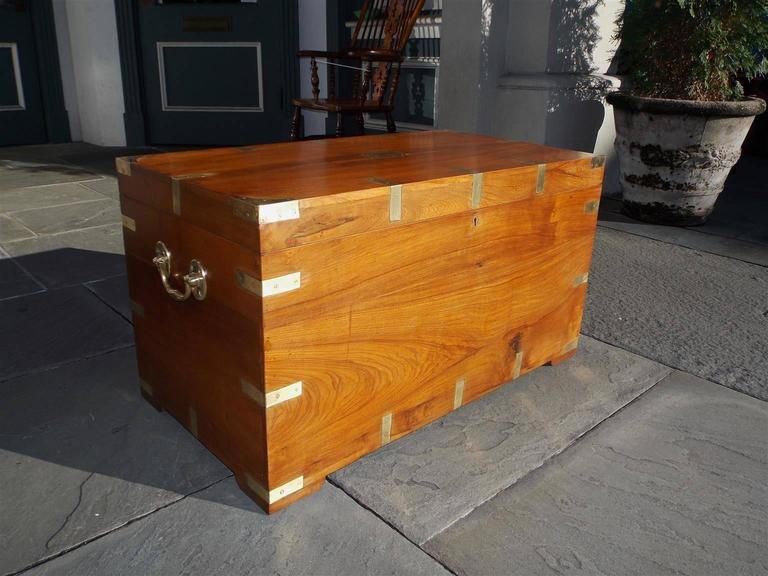American teak Campaign trunk with hinged top, original brass corner mounts, brass side handles, locking mechanism with key, and terminating on original bracket feet. Trunk is finished on all sides, Late 18th century.