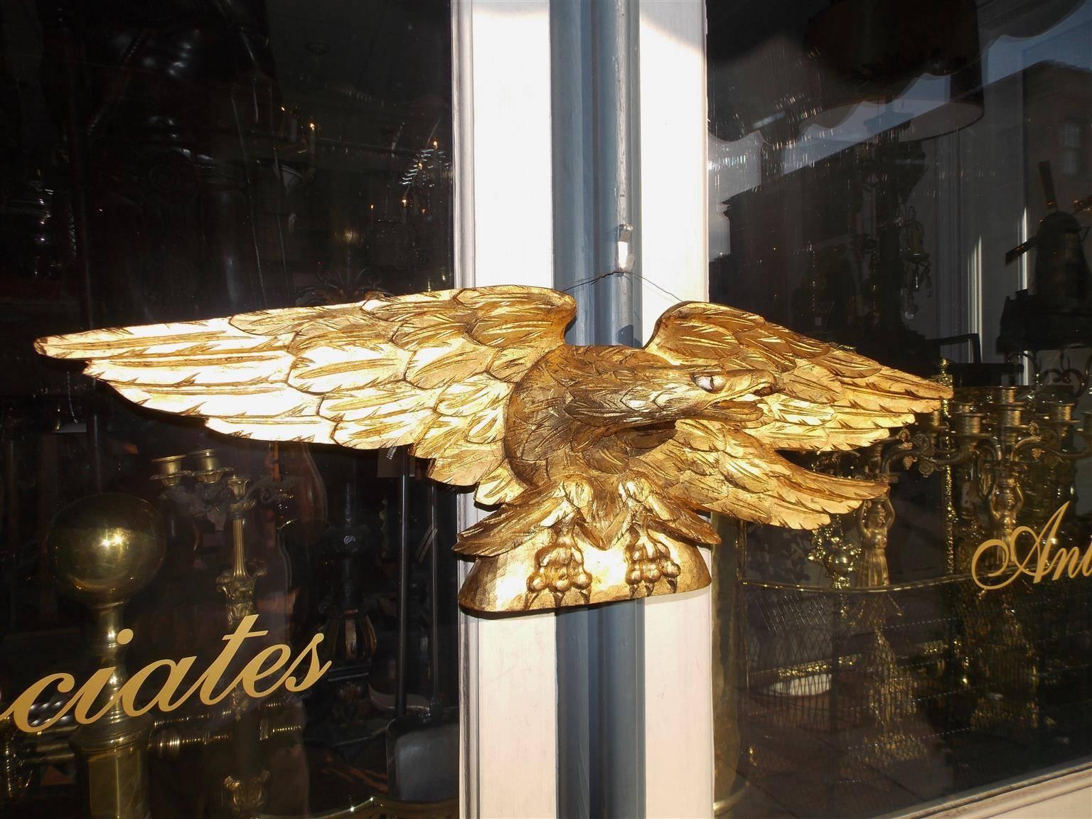 American gilt carved wood eagle with extended wings perched on rounded plinth, Early 19th Century.