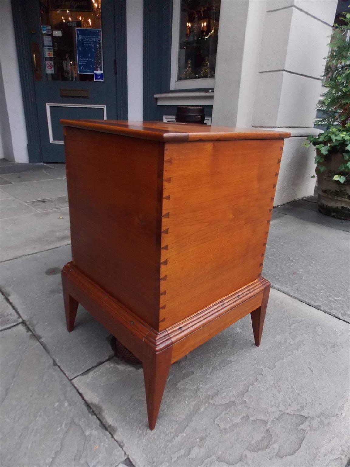 American walnut hinged sugar chest with exposed exterior dovetails and resting  on the original incised molded edge stand with pointed cone feet. Secondary wood consist of Tulip poplar. Early 19th Century, Tennessee / Kentucky.