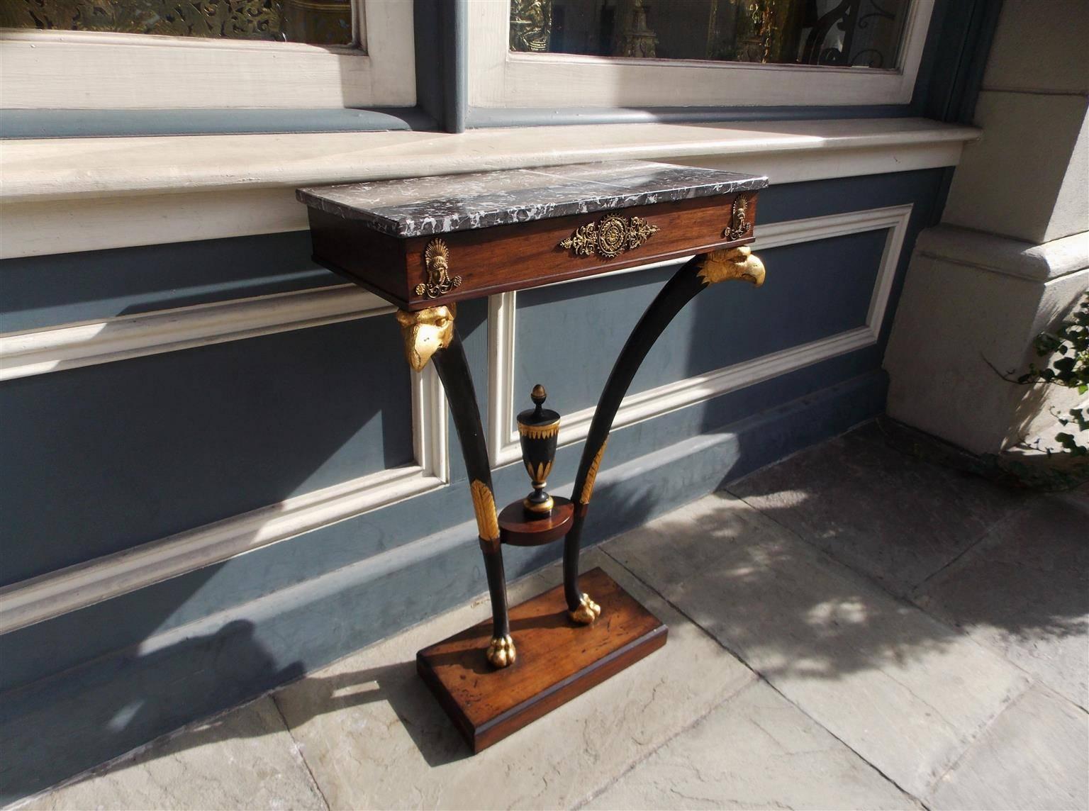 English Regency mahogany marble-top console with flanking Phoenix heads, original ormolu mounts, ebonized tapered legs, centered gilt urn and terminating on rectangular molded edge base with stylized claw feet, Late 18th Century. 
Measures: Marble