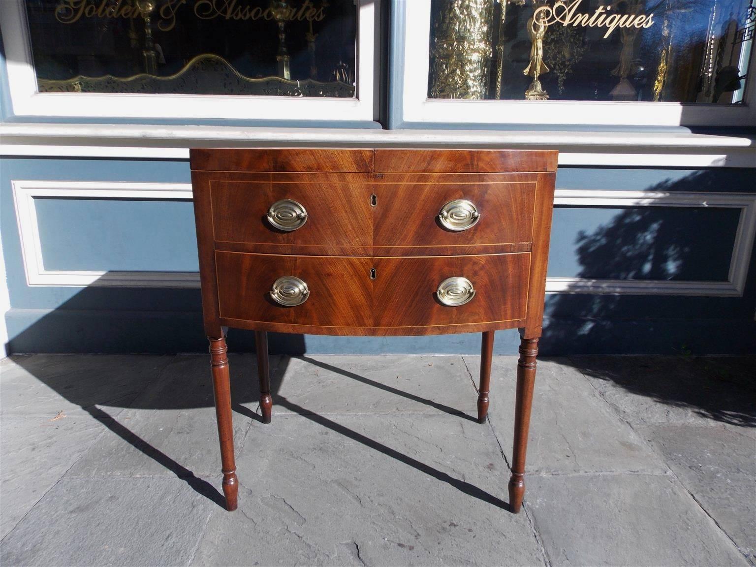 English mahogany bow front ladies dressing table with hinged top, single drawer, original brasses, satin wood inlay, compartmentalized fitted interior with oval folding mirror, terminating on turned bulbous ringed legs.  Late 18th Century. Table is