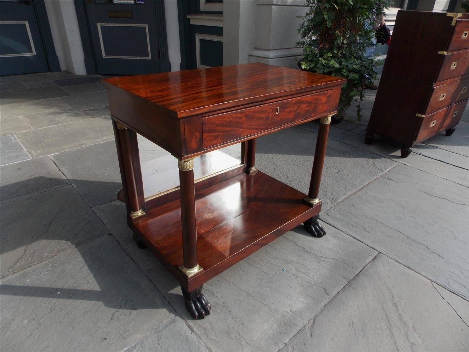 French mahogany one-drawer console with one board top, original ormolu mounts, original brass banded mirrored back, turned columns, lower shelf, and terminating on ebonized lions paw feet, Late 18th century. Console is finished on all sides.