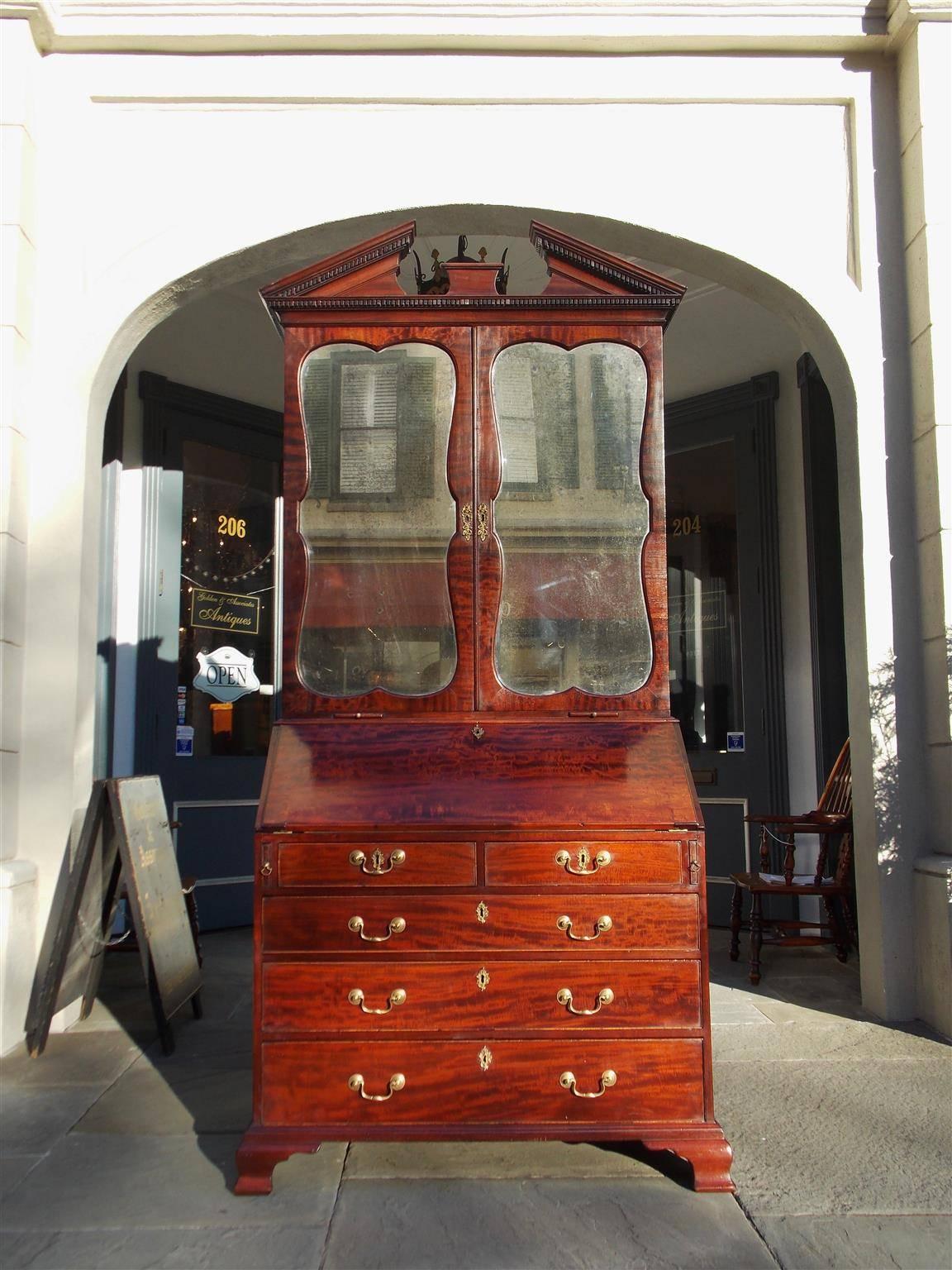 English mahogany secretary with mirrored bookcase. Secretary has a upper case broken pediment top with dental molding, original mirrored doors, candle slides, and  fitted interior with adjustable shelving.  The lower case consist of a slant front