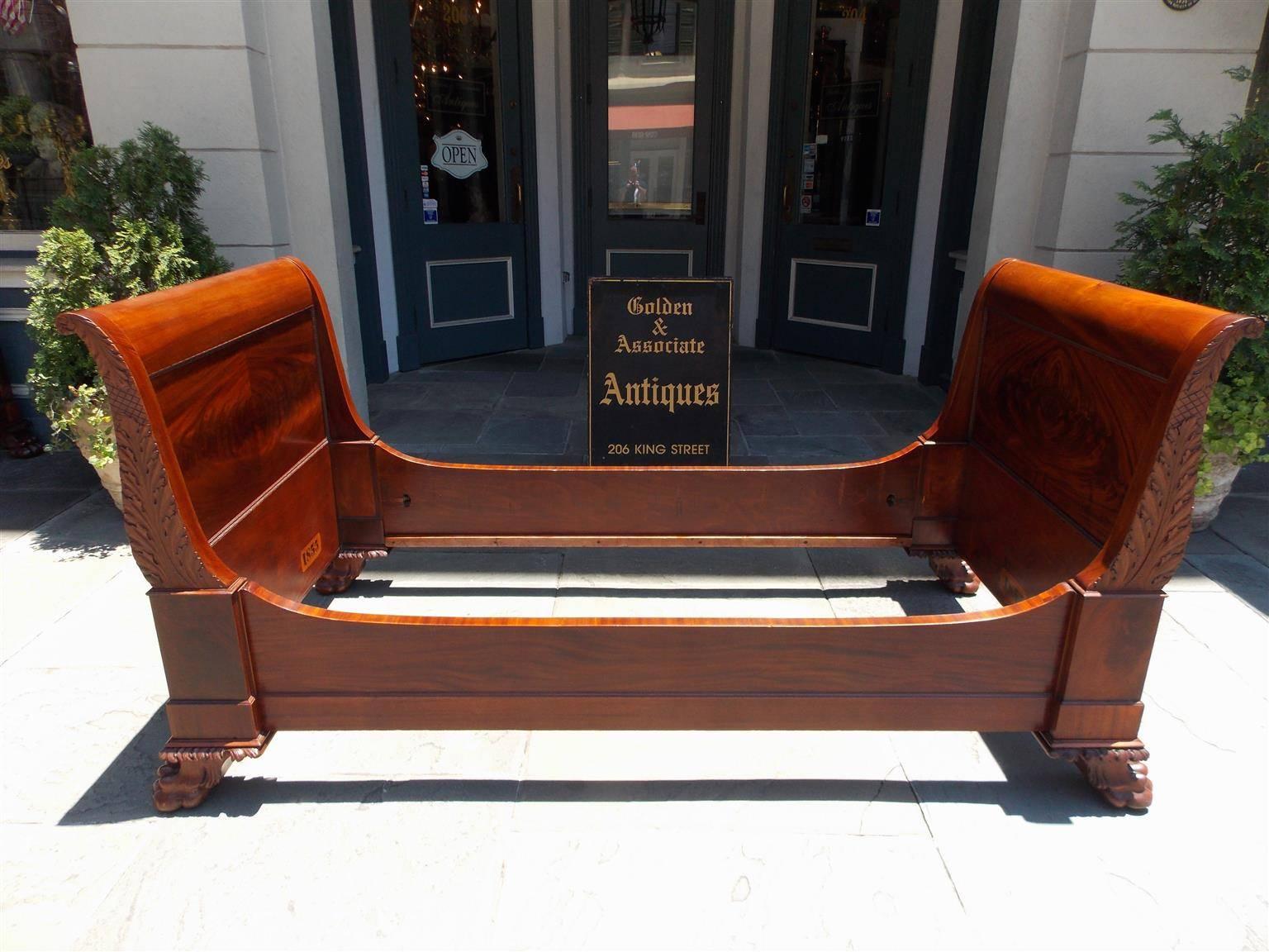 Pair of American Cuban mahogany twin sleigh beds with book matched head and foot boards, carved acanthus scrolled arms with cross hatching, gadrooned beading on molded edges, and terminating on acanthus carved lions paw feet. Stamped 1855, Mid-19th