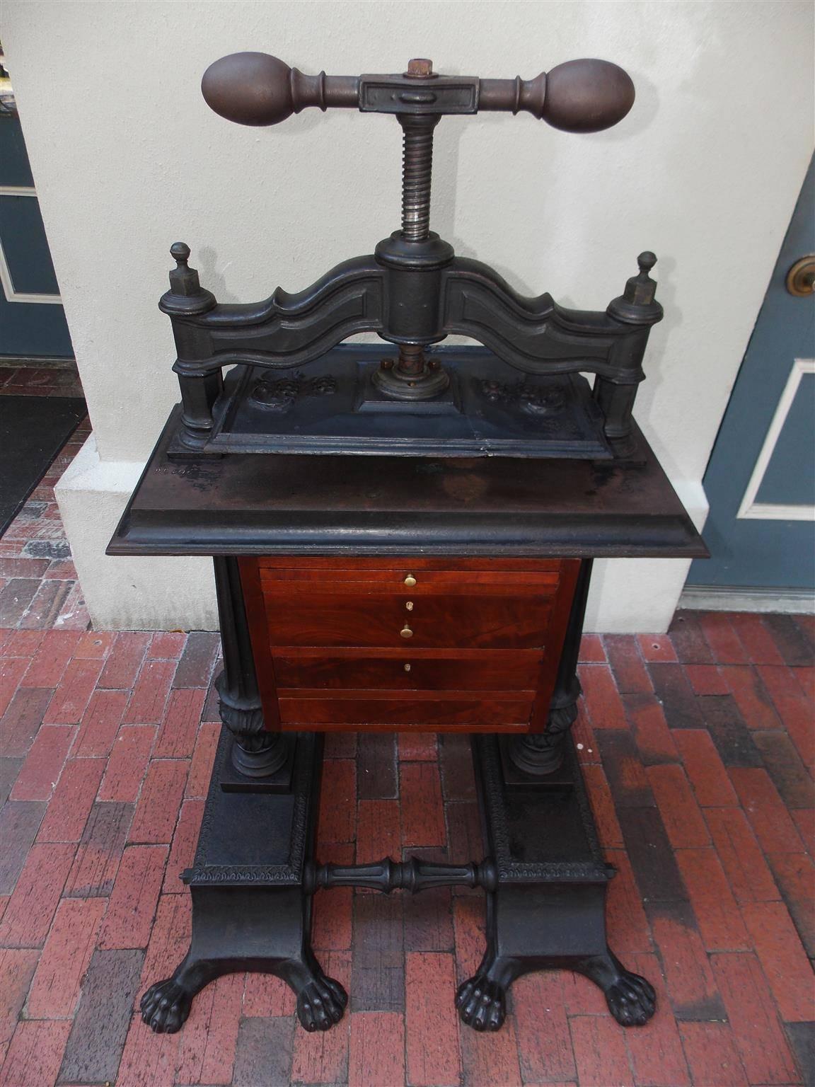 American cast iron and mahogany two-drawer copying press with a turned bulbous cork screw handle, floral decorative pressure plate, flanking fluted decorative side columns, and resting on flanking rectangular plinths with the original eight lions