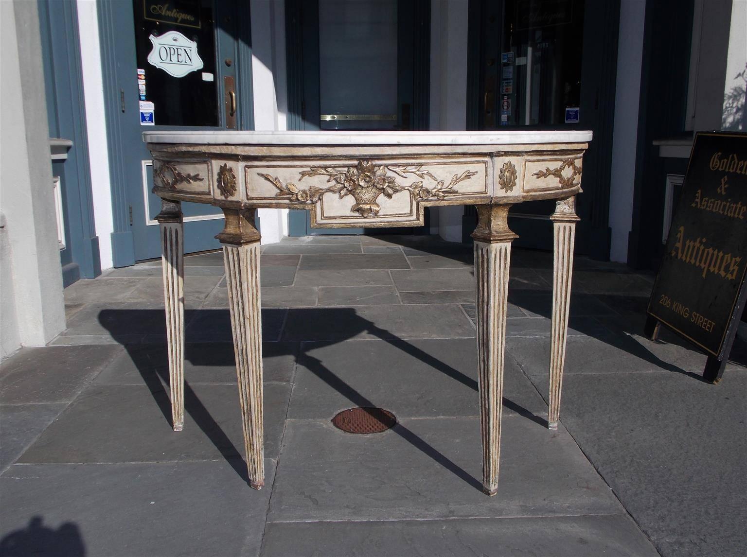 Italian carved wood, painted, and gilt marble top console with centered floral basket ending on fluted legs. All original
