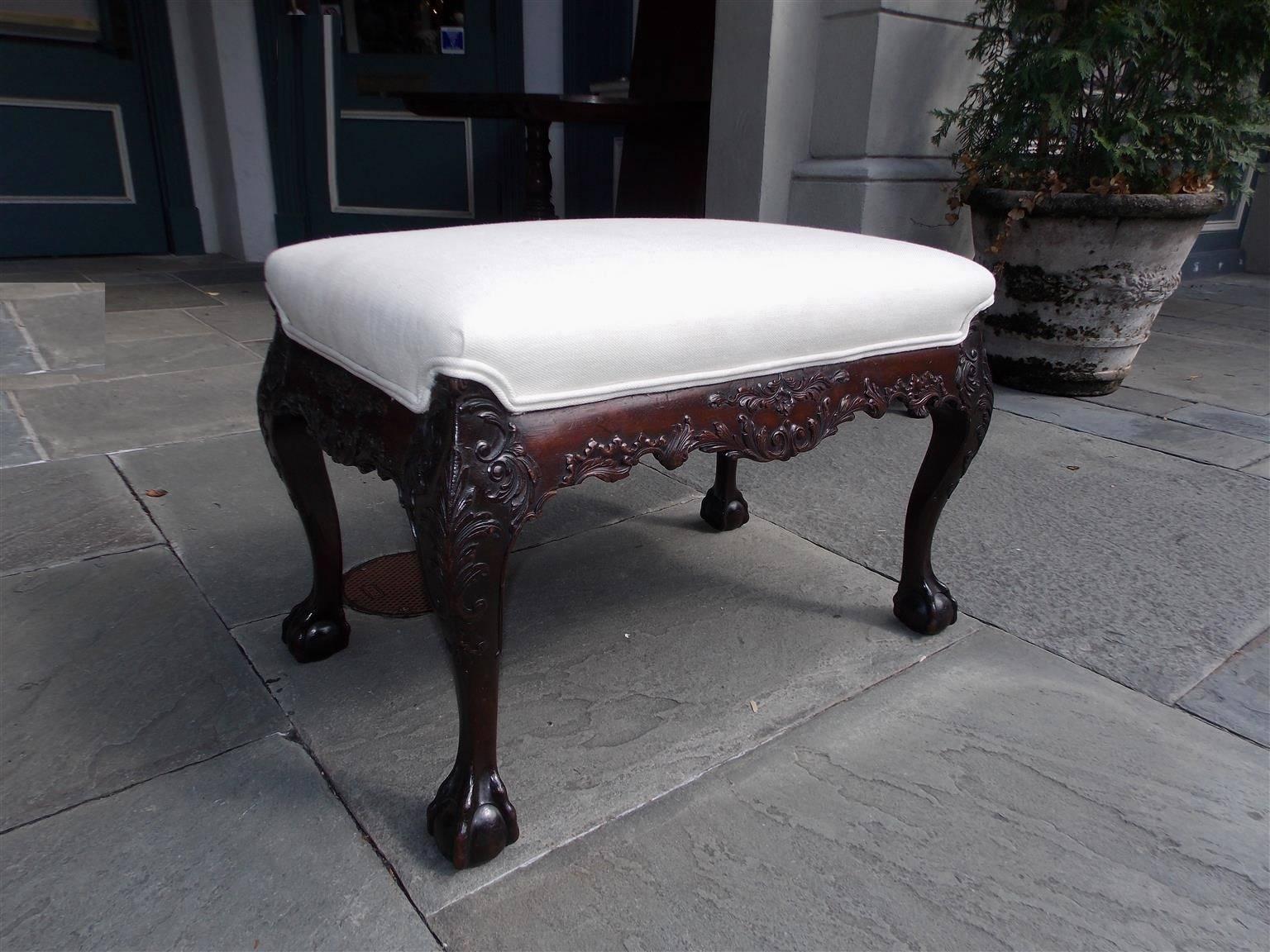 Irish Chippendale mahogany window bench with carved scalloped acanthus floral skirt, acanthus carved floral knees and terminating on tampered rounded legs with claw and ball feet. Bench is upholstered in white muslin with double piping, Late 18th