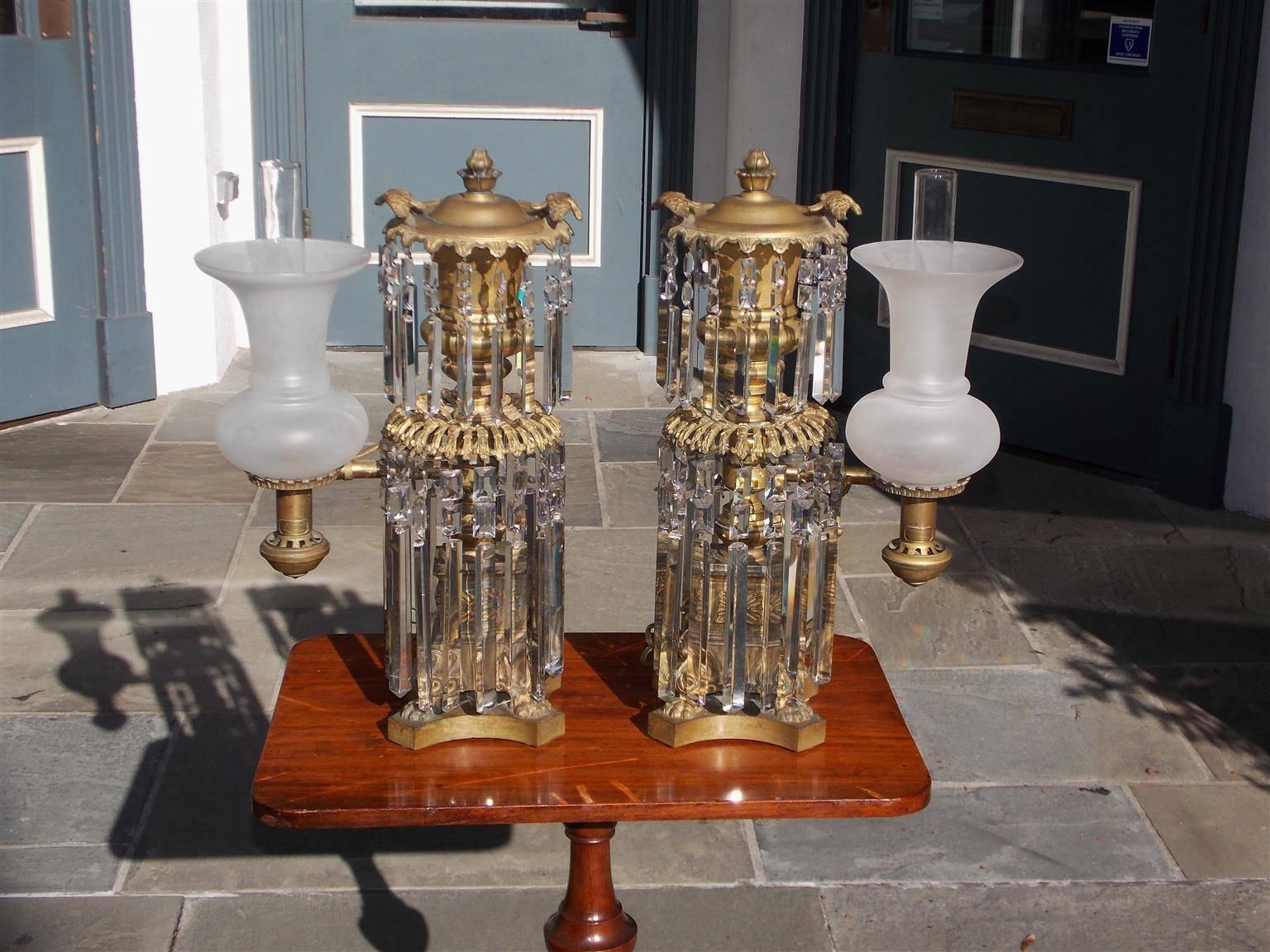 Pair of American gilt bronze and crystal Argand lamps with a centered urn a top columns, each with flanking single arms, foliate-edged rings with bird motif, lotus finial, matching frosted glass shades with cylindrical glass chimneys, and resting on
