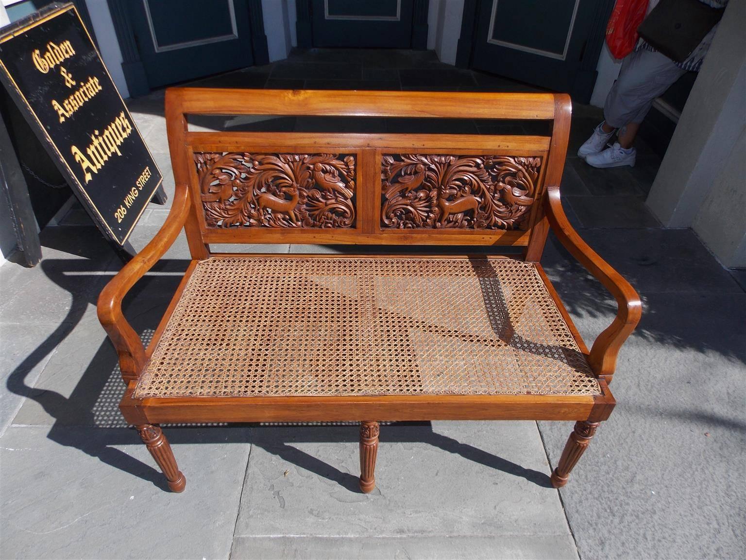 Caribbean kings wood settee with a scrolled back, flanking panels with carved foliage and animal motif, original cane seat and terminating on turned bulbous reeded ringed legs. Early 19th Century.
Seat depth is 21.5