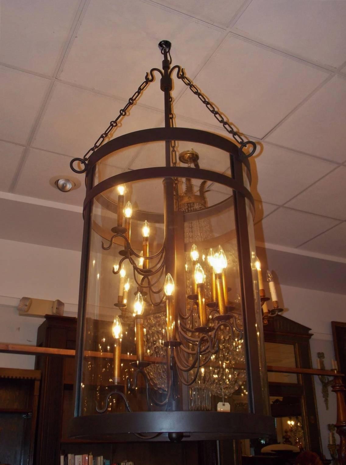 American cast iron cylinder hanging lantern with twelve interior lights, three paneled glass, suspended by decorative cast chain. Early 20th Century.