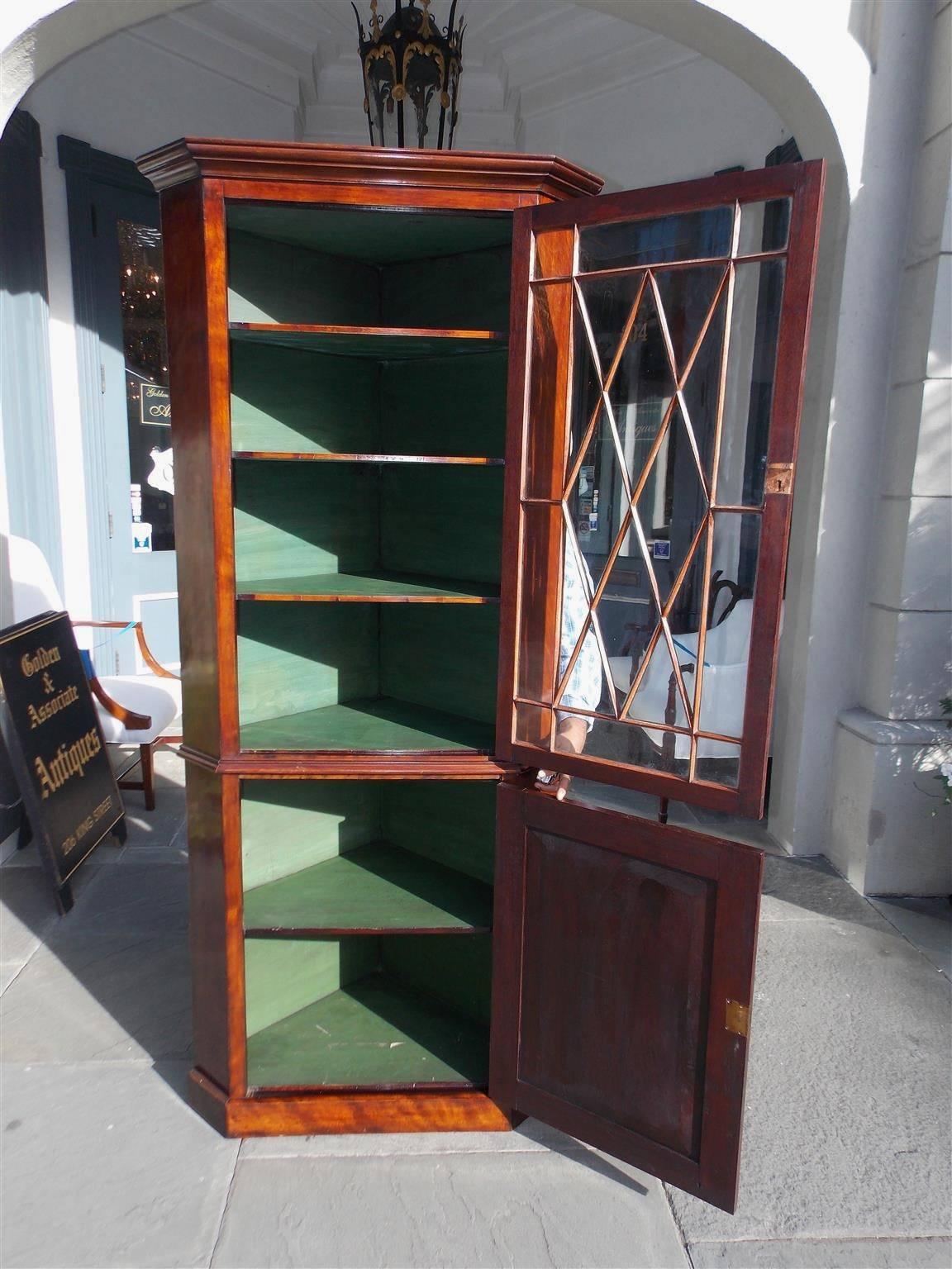 American Federal mahogany diminutive corner cabinet with a carved molded edge cornice, upper hinged mullion glass door with three fitted interior shelves, lower hinged blind door with a single fitted interior shelf, all resting on the original