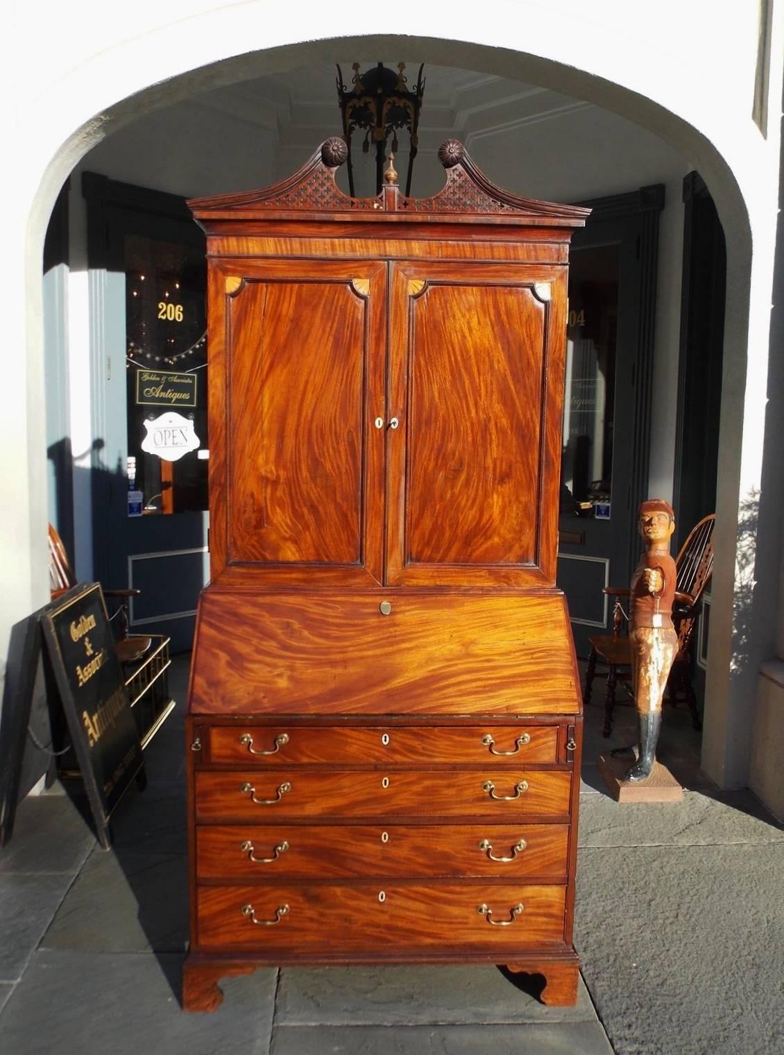 English mahogany secretary with bookcase. Upper case has a intricately carved broken pediment with floral medallions and centered urn, patera satinwood inlaid blind doors, with upper case interior adjustable shelves. The lower case has a slant front