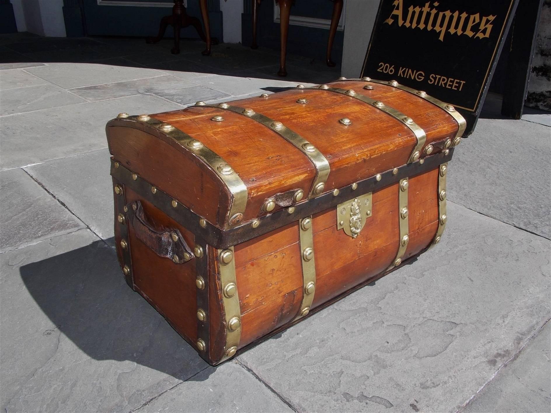 American white pine hinged traveling trunk with an exterior bowed top and bottom, the original brass mounts, leather side handles, locking mechanism and iron straps, Early 19th Century.
