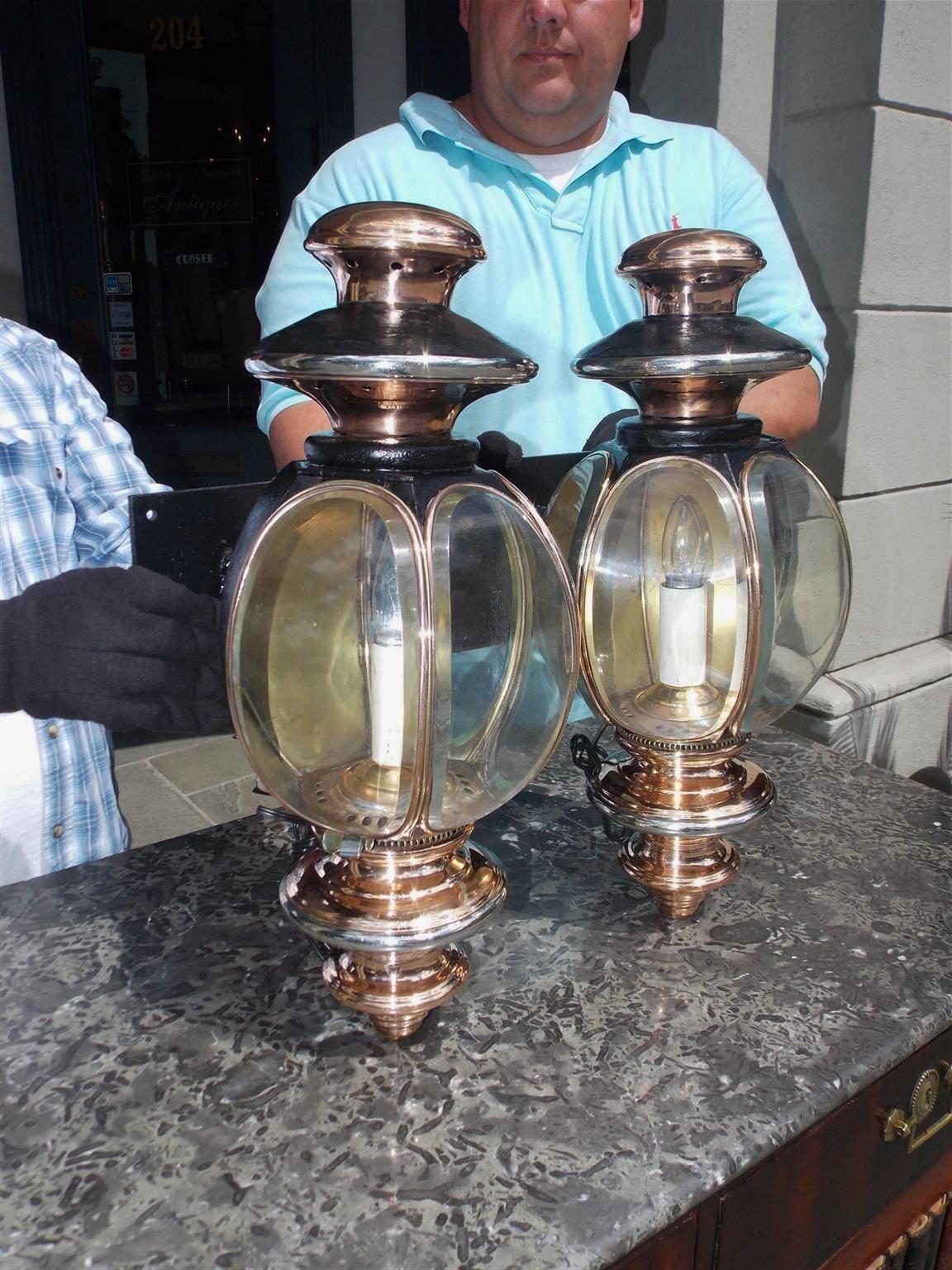 Pair of American nickel silver and copper coach lanterns with vented tiered upper finials, the original oval beveled glass, bead work, vented lower tiered finials , and mounted on square wrought iron wall brackets, Mid-19th century, New Haven,