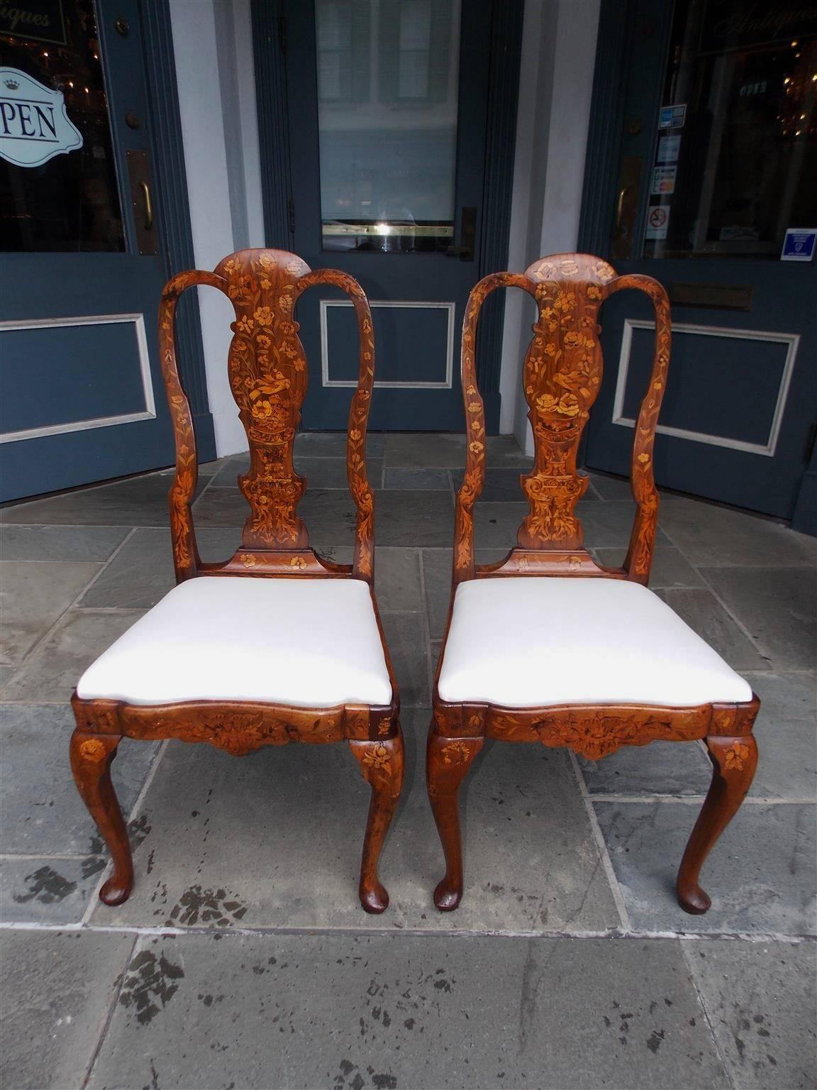 Pair of English Queen Anne walnut marquetry side chairs with scrolled inlaid side rails, vase form floral and bird inlaid decorative backs, carved scalloped inlaid skirts, and terminating on the original tapered legs with pad feet, Mid-18th century.