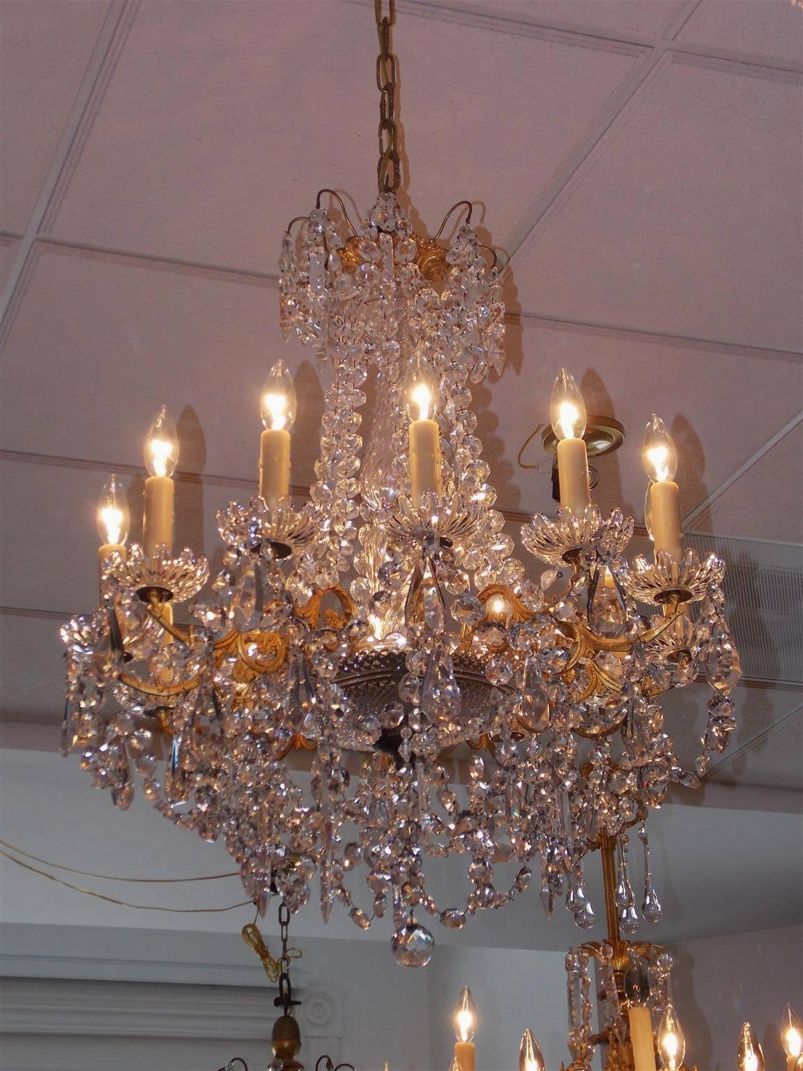 French Baccarat gilt bronze and crystal twelve-arm chandelier with a gilt floral canopy, cascading crystal prisms flanking a centered spiral crystal column , twelve gilt floral scrolled arms with the original crystal bobèches, and resting on the